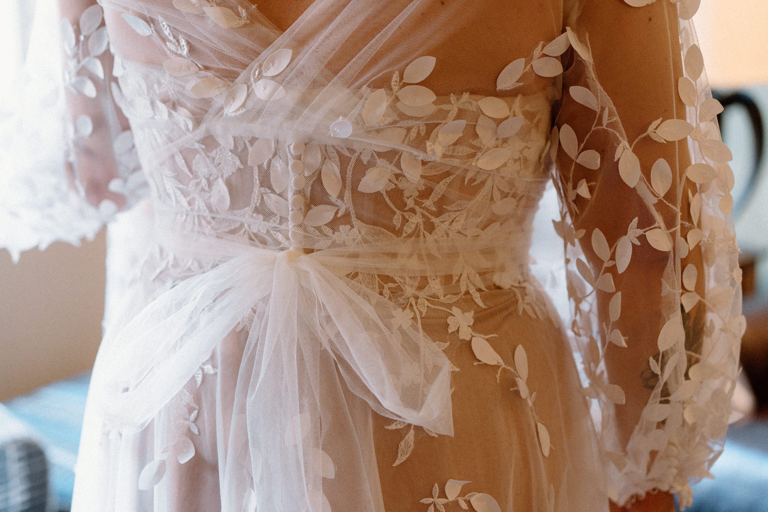 A close up of the buttons and lace of the wedding dress