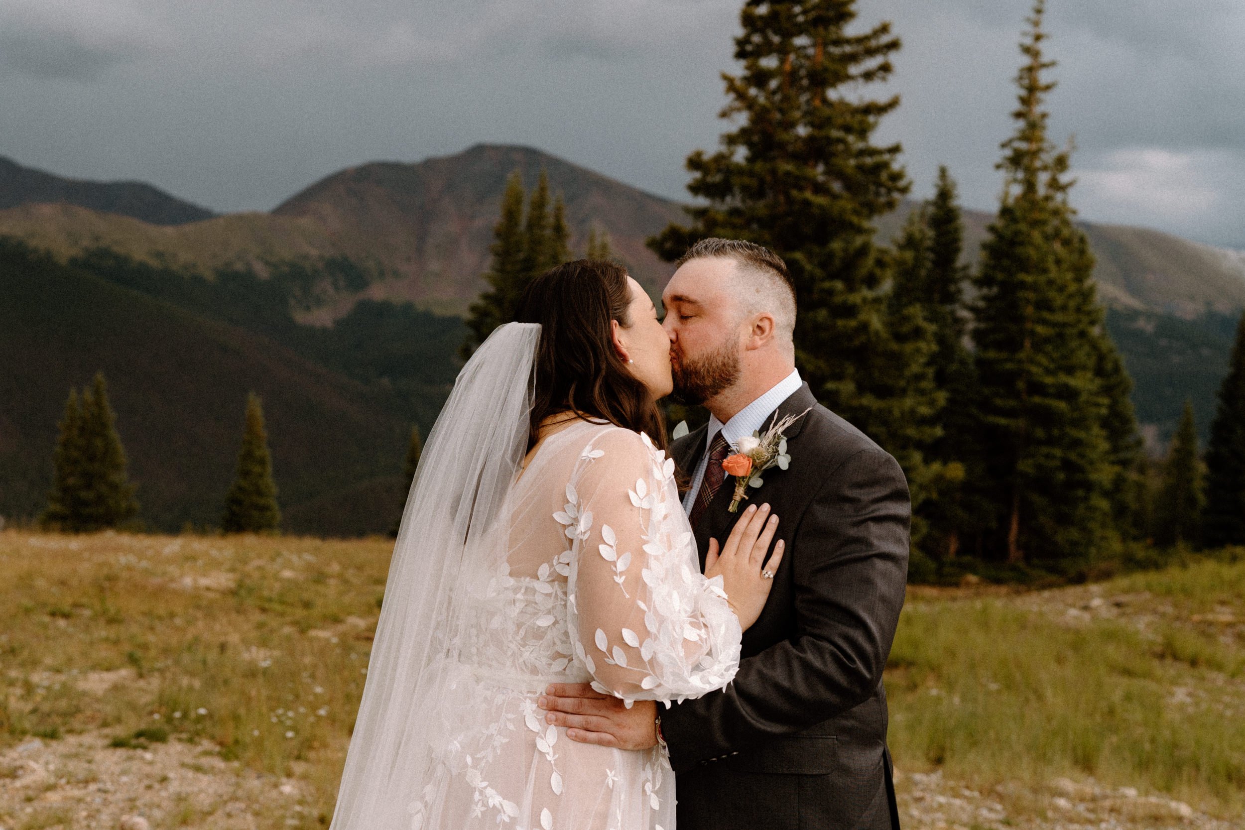 Bride and groom kiss in the mountainside at Lunch Rock in Winter Park, CO
