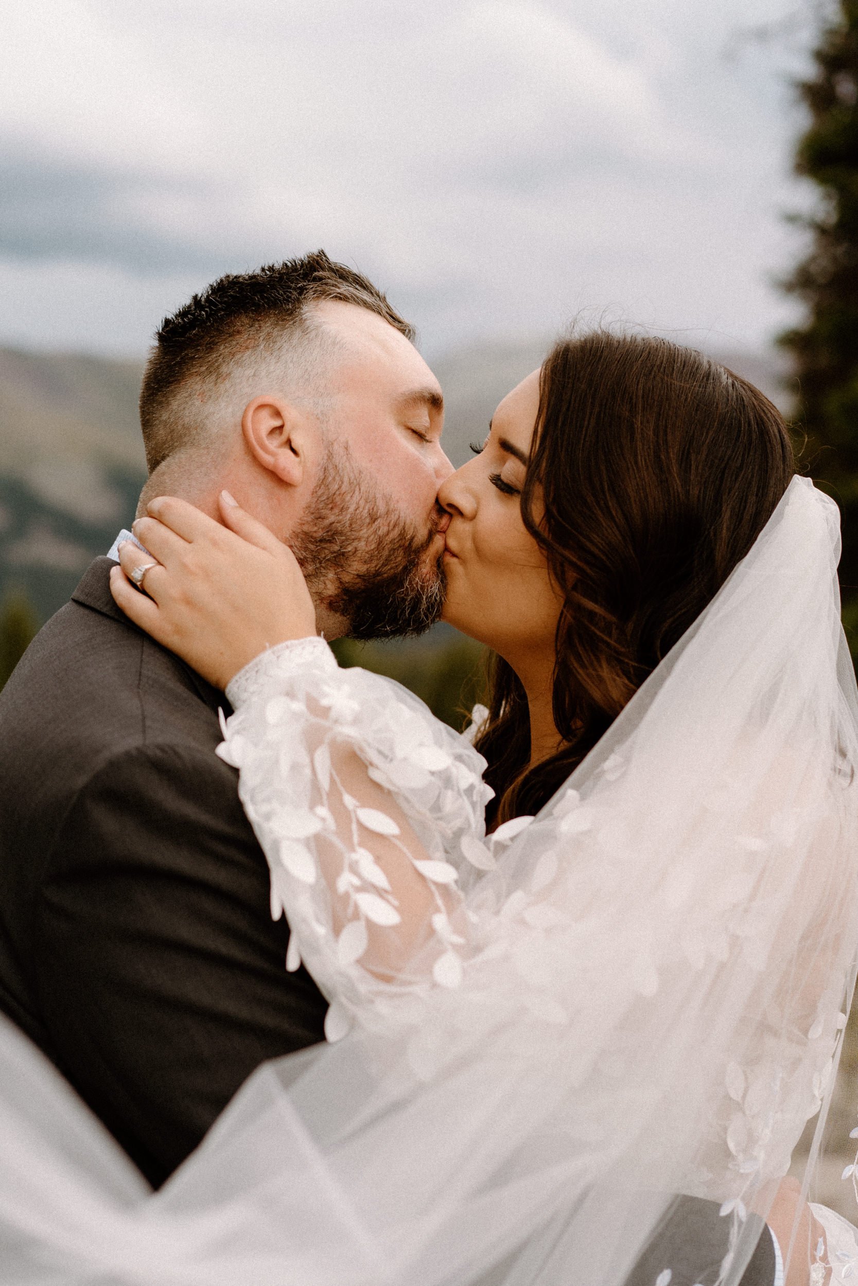 Bride and groom kiss as her veil envelops them