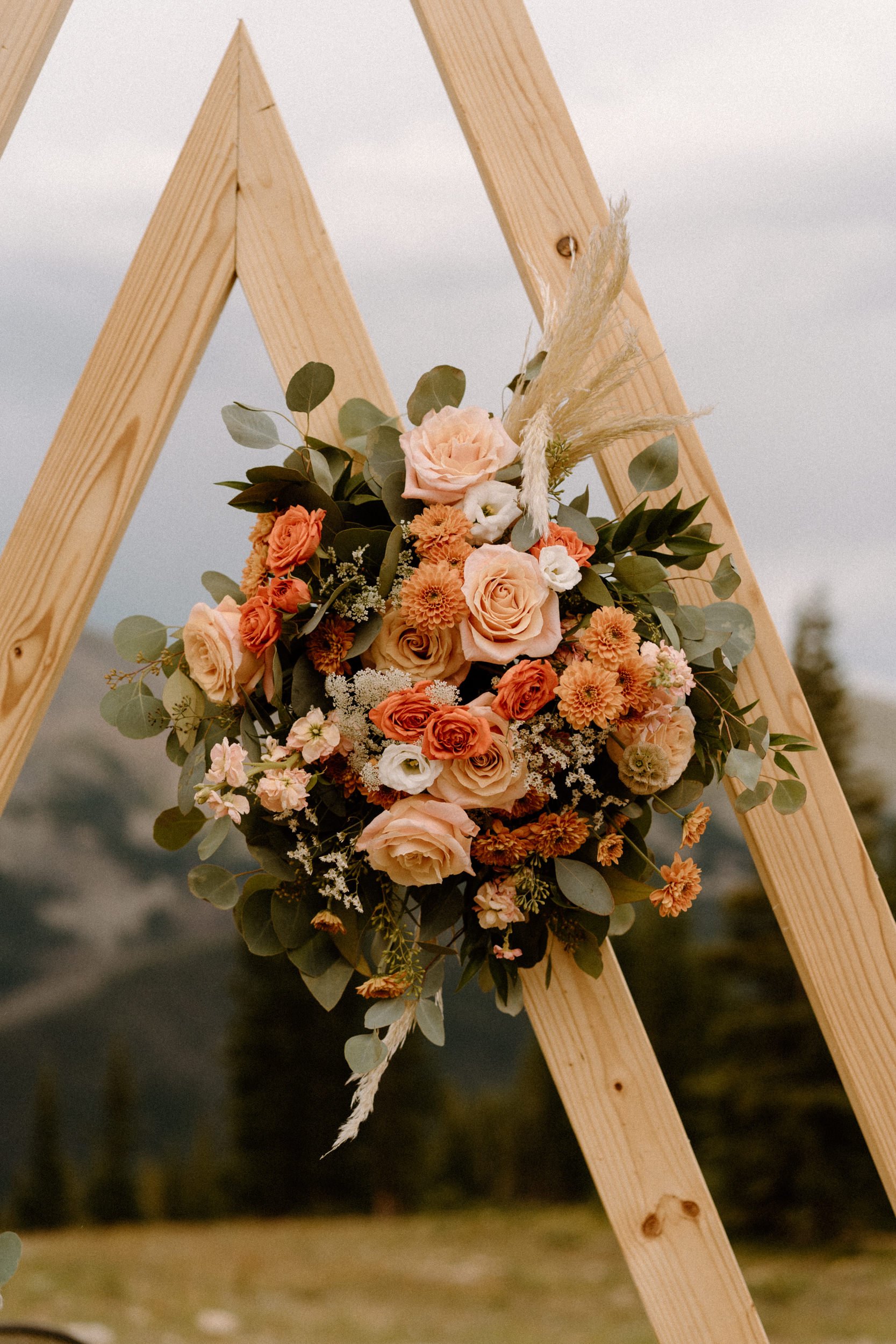 Pink and orange flower bouquet on the wooden triangle altar