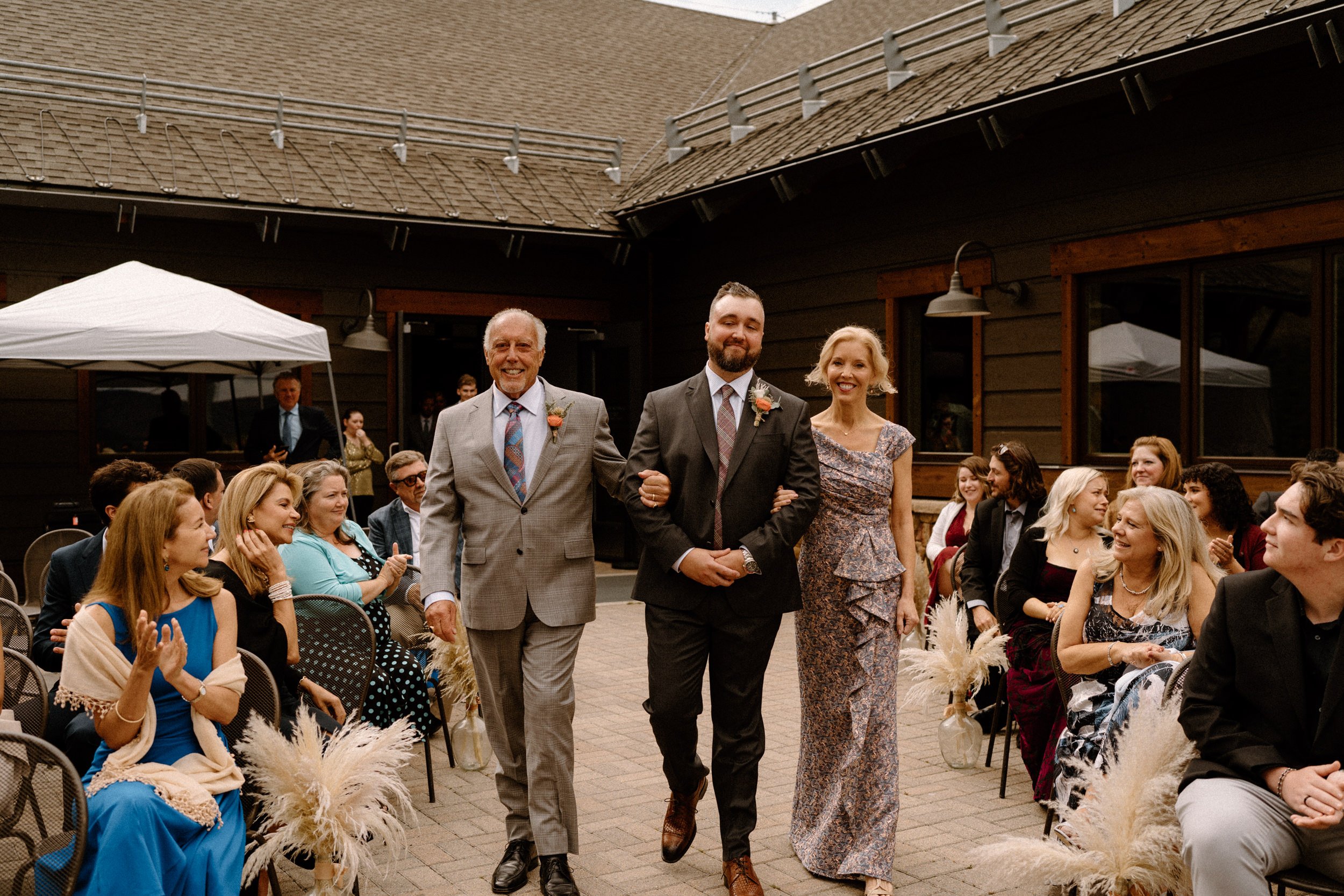 Groom walks down the aisle with his parents