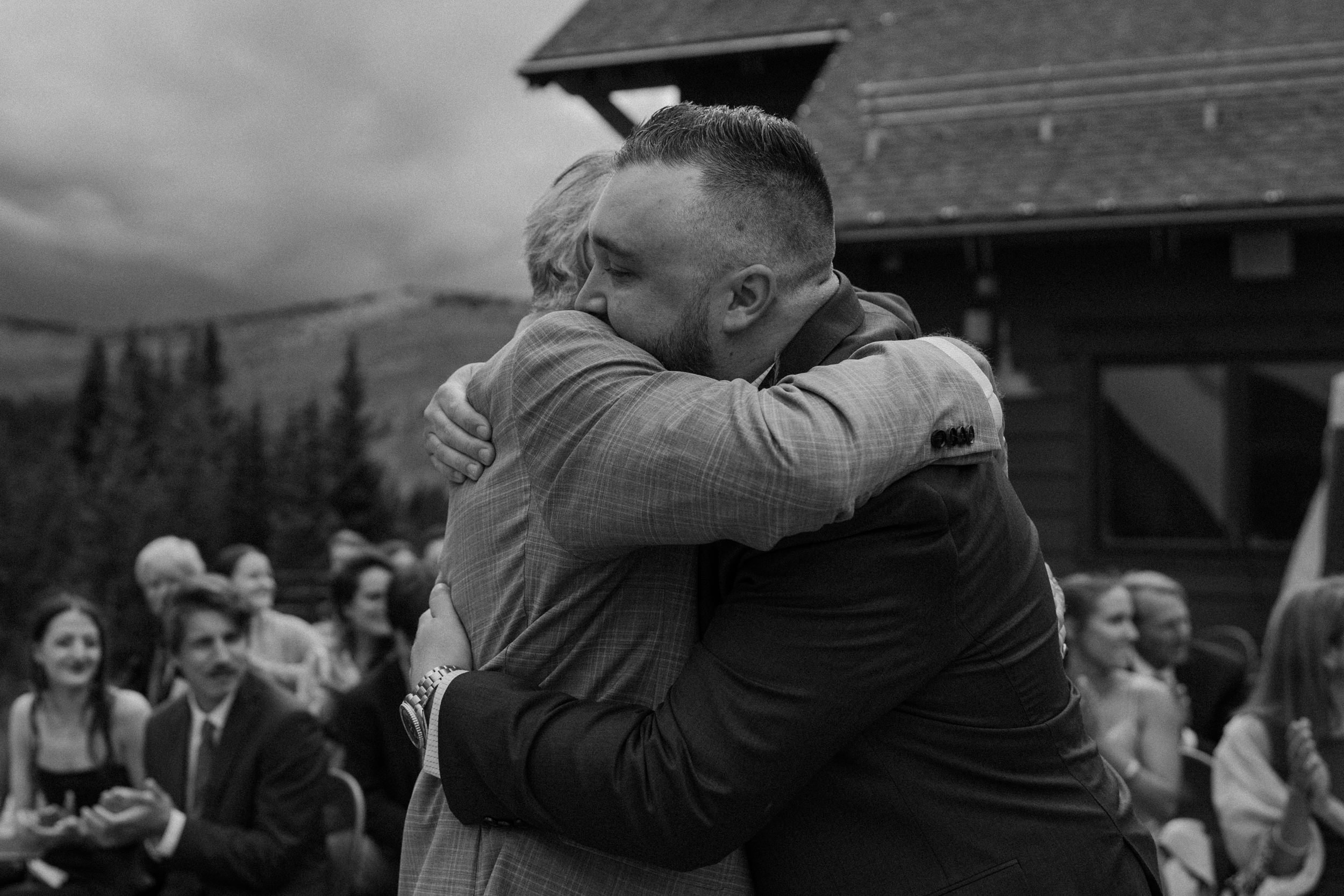 Groom hugs his father at the end of the aisle