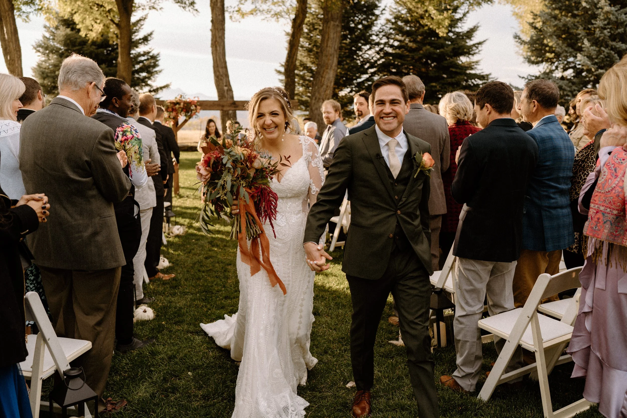 The bride and groom walk down the aisle together and smile