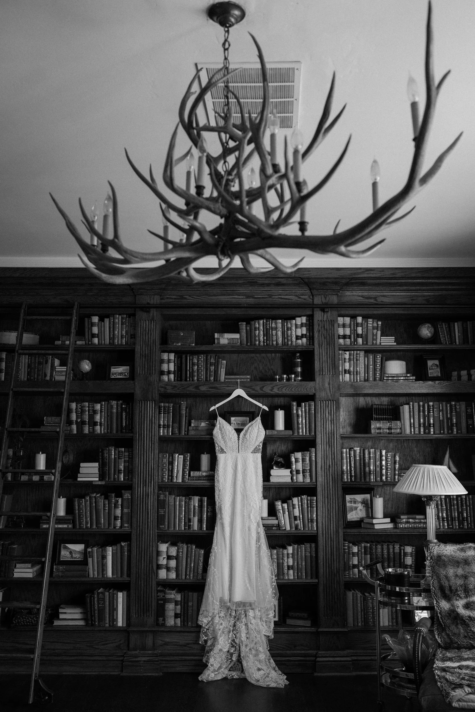 Bride's dress hanging on bookshelf on wedding day at The Manor House
