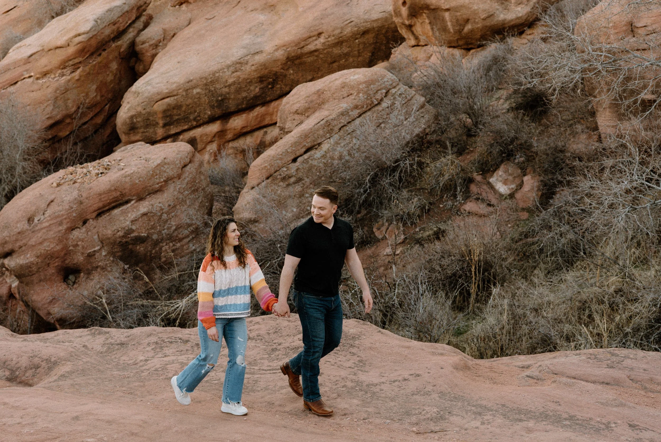 Couple walking and smiling during an engagement session at Red Rocks