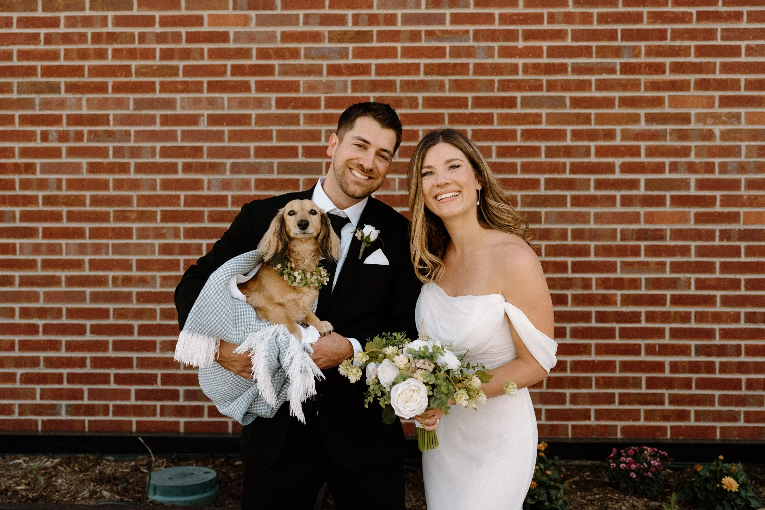 Bride and groom smiling with their dog on wedding day at The Eddy in Golden Colorado