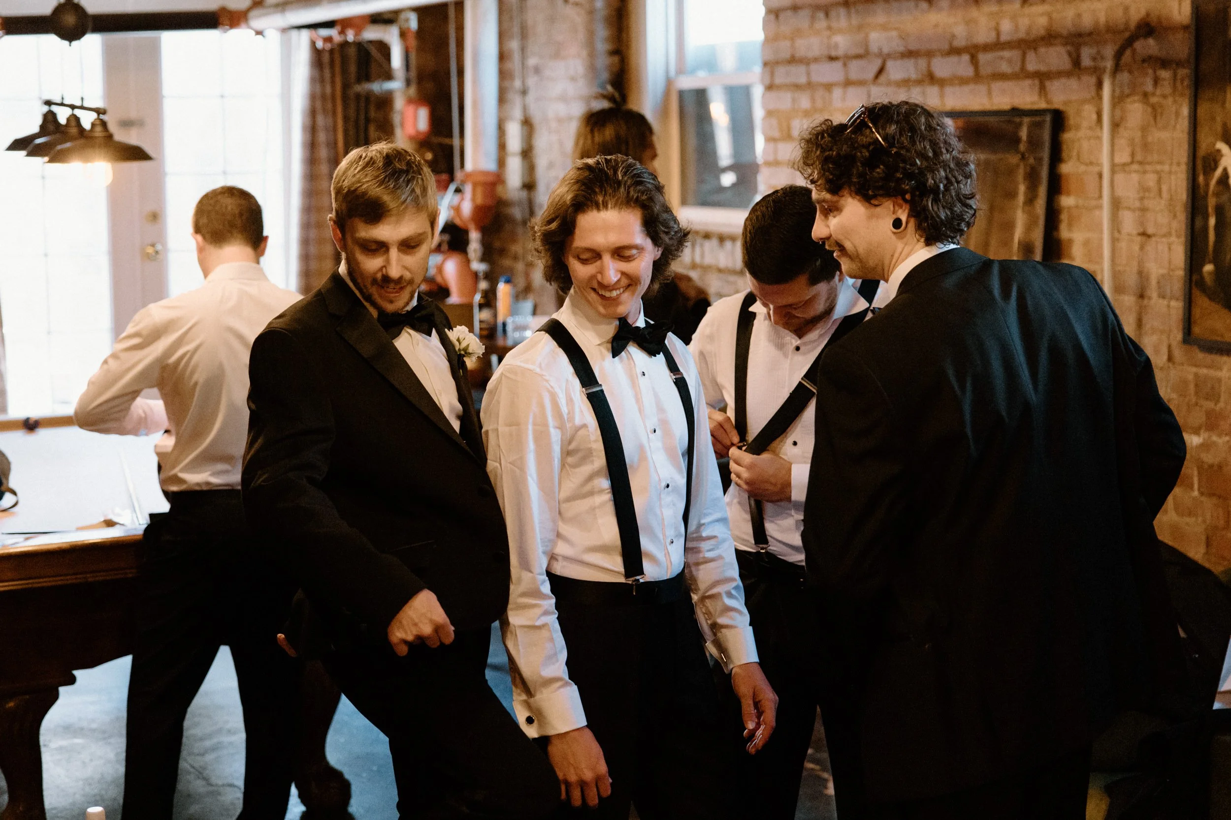Groom and groomsmen smiling while getting ready on wedding day at The Manor House