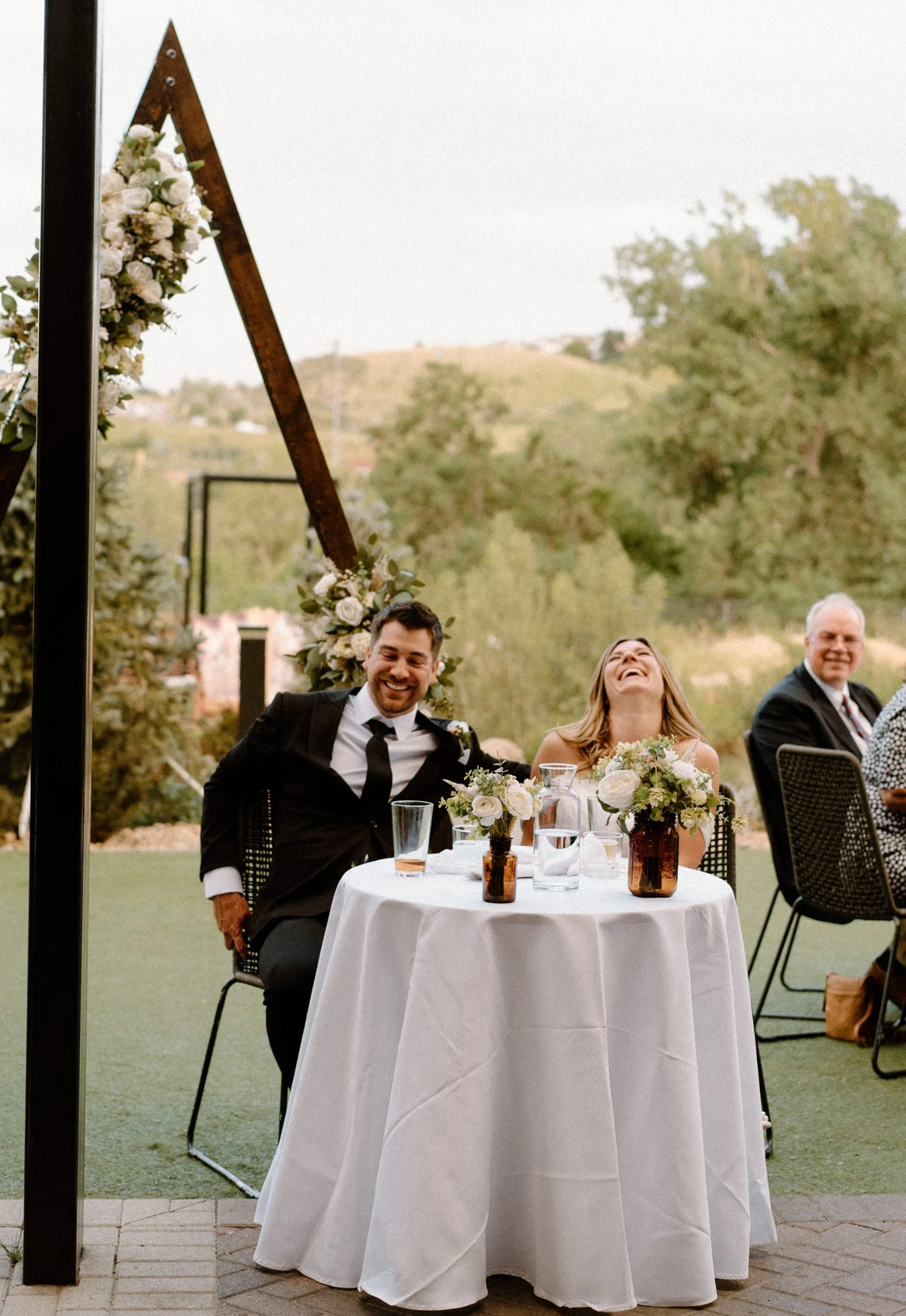 Bride and groom laughing during speeches at The Eddy Hotel on wedding day in Golden Colorado