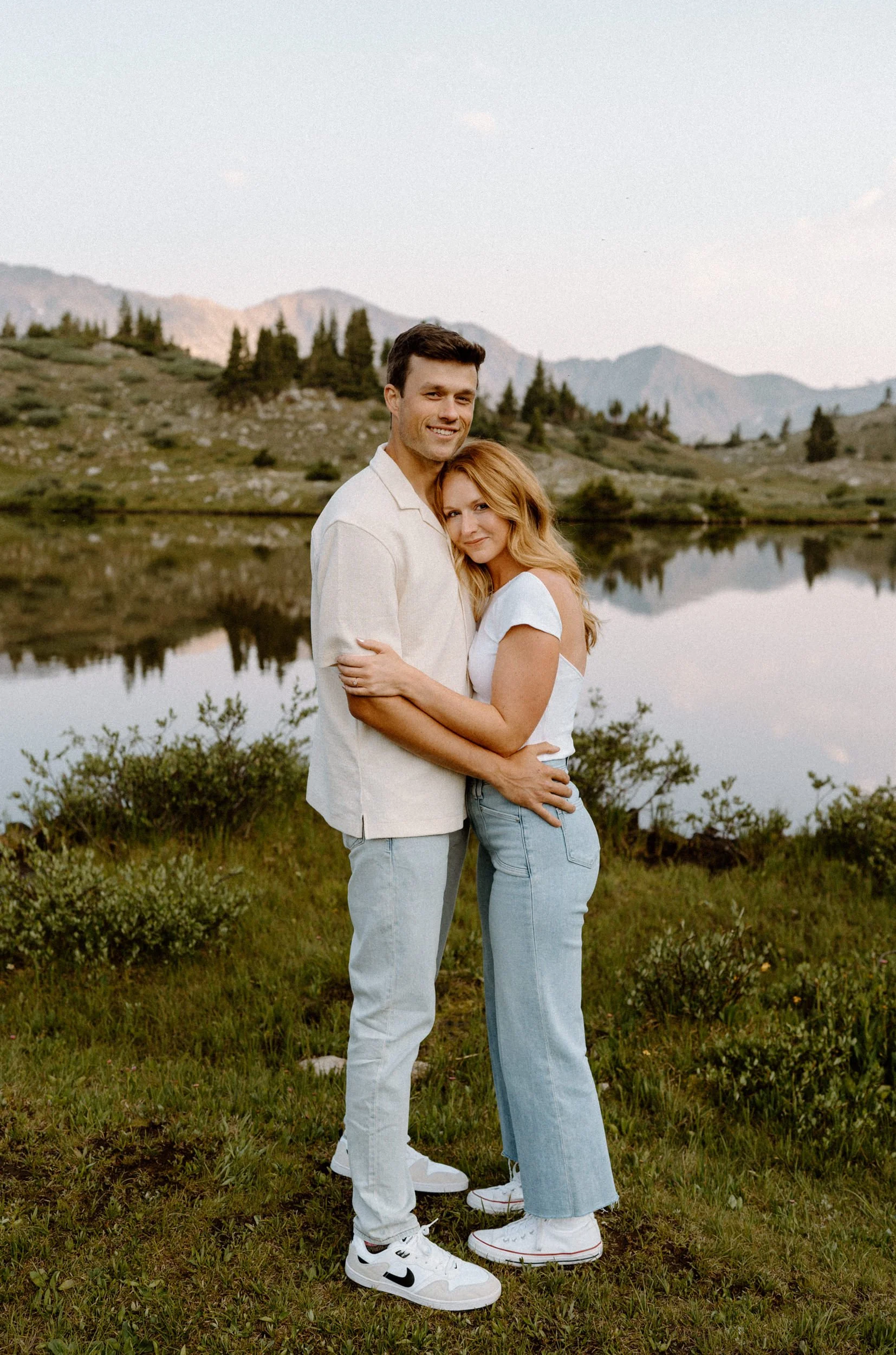 Couple hugging in a field during an engagement session at Loveland Pass