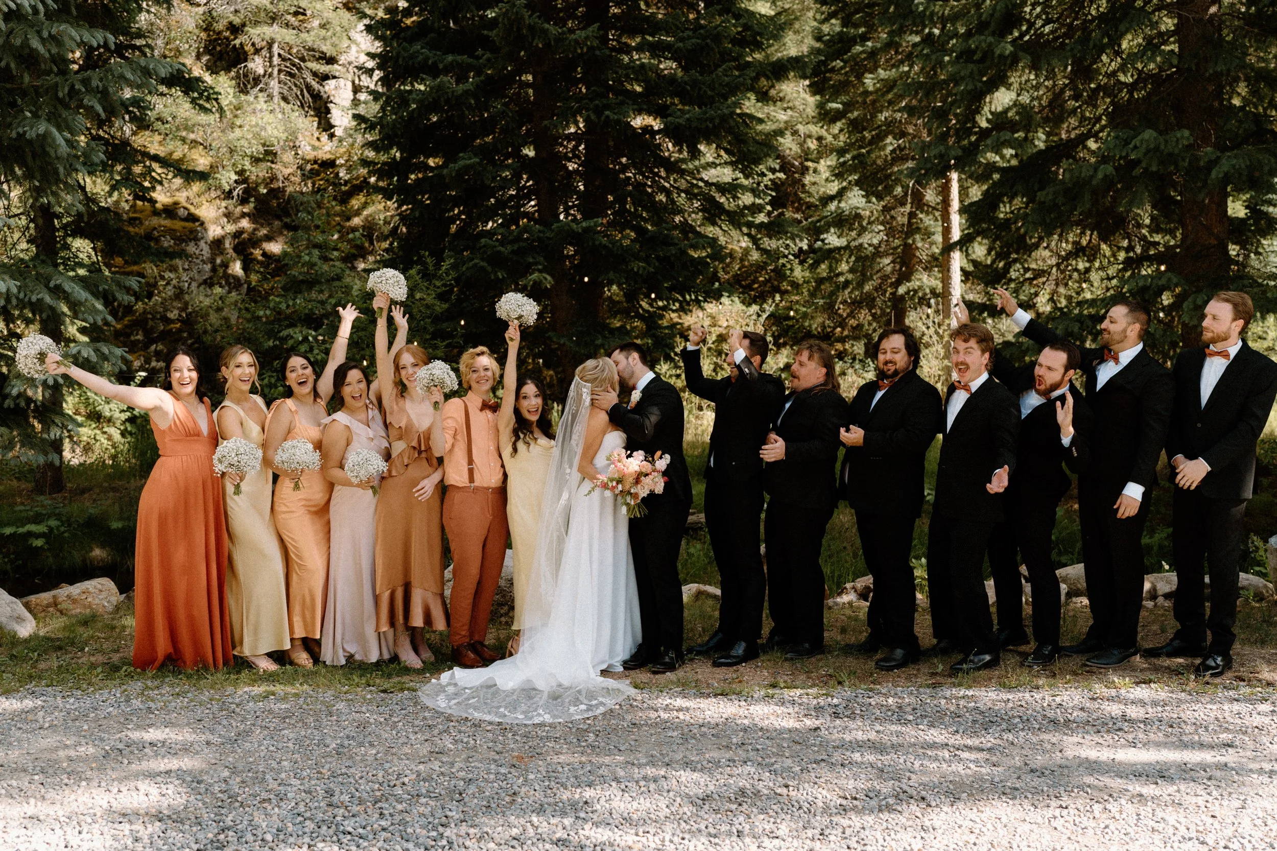 Bride and groom kiss while wedding party cheers during a wedding at Blackstone Rivers Ranch