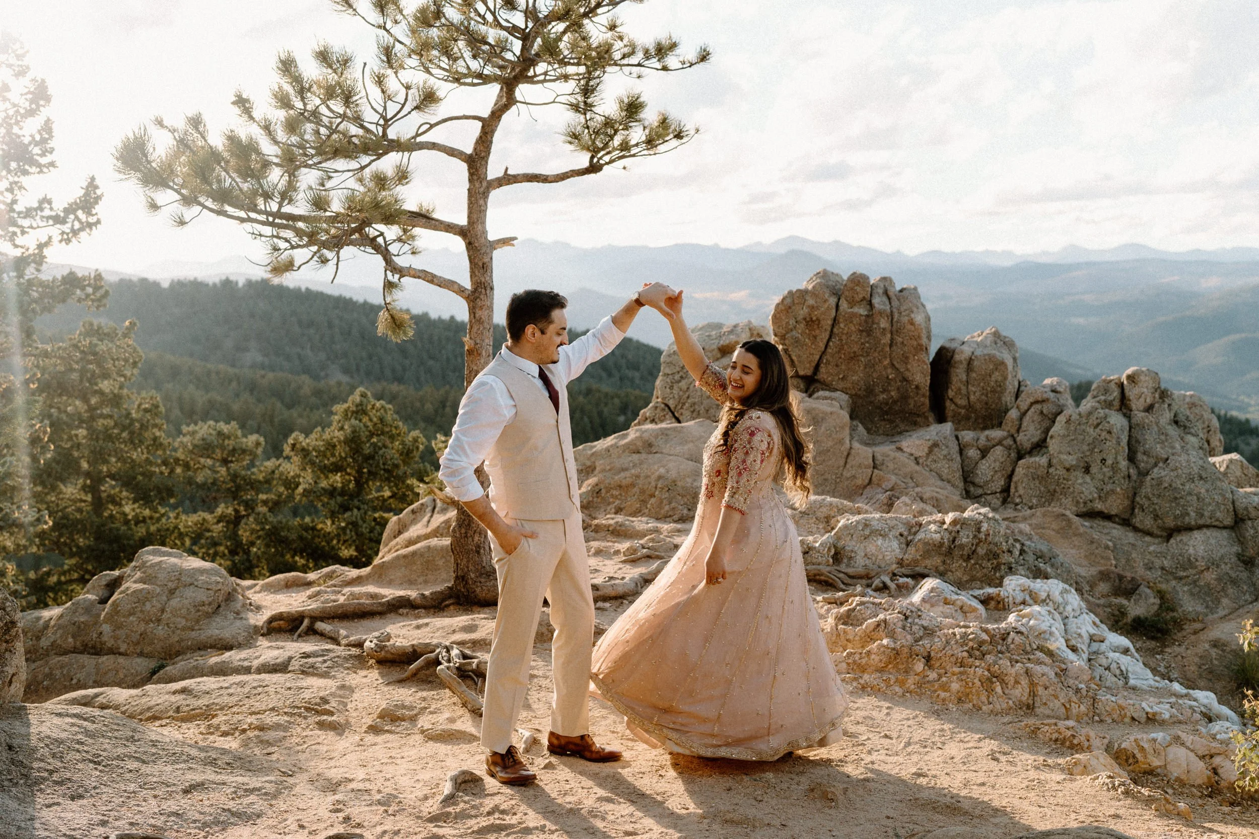 Fiancé twirling his fiancée on top of a mountain during an engagement session in Boulder Colorado