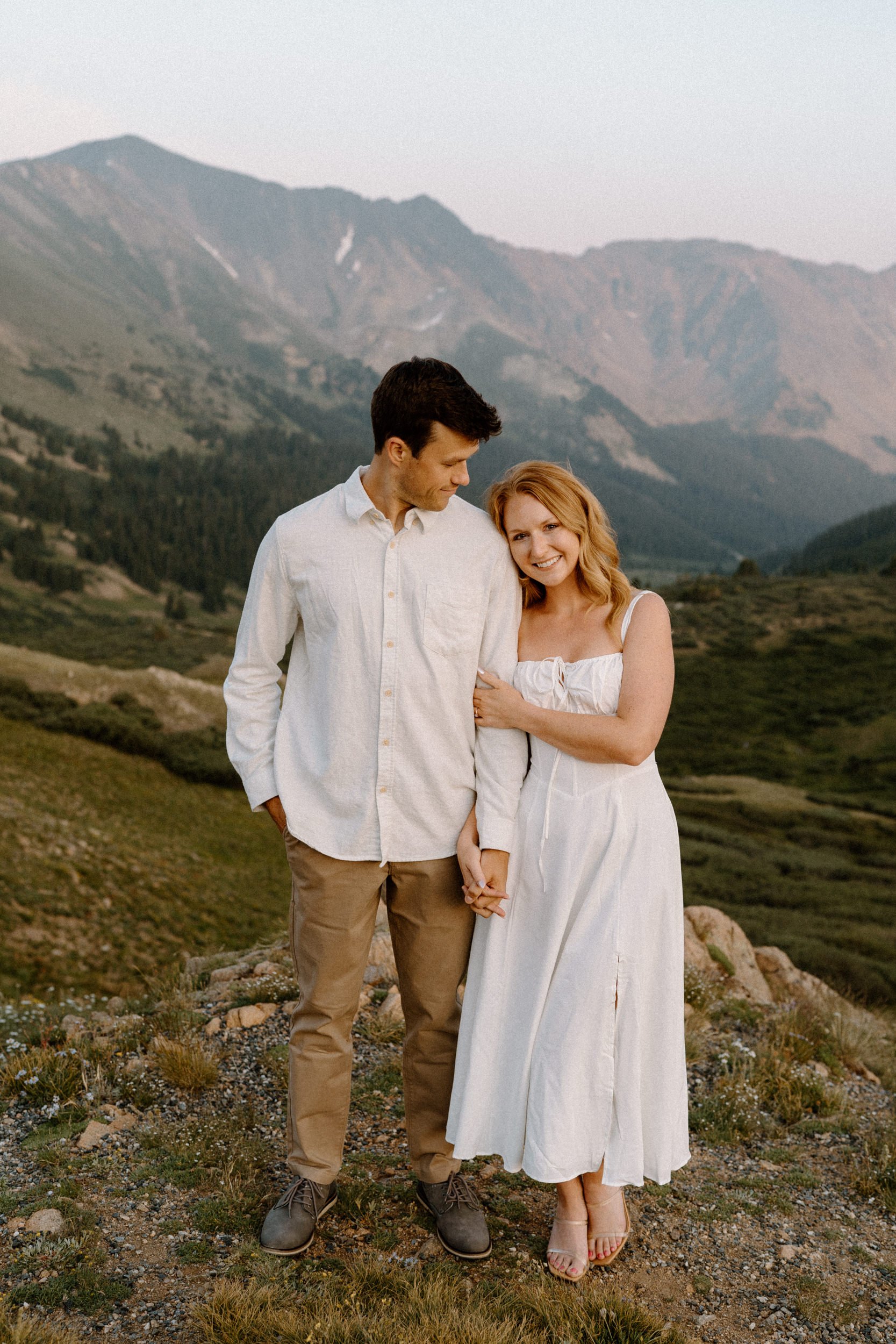 Fiancée smiling at the camera while fiancé smiles at her during engagement session at Loveland Pass