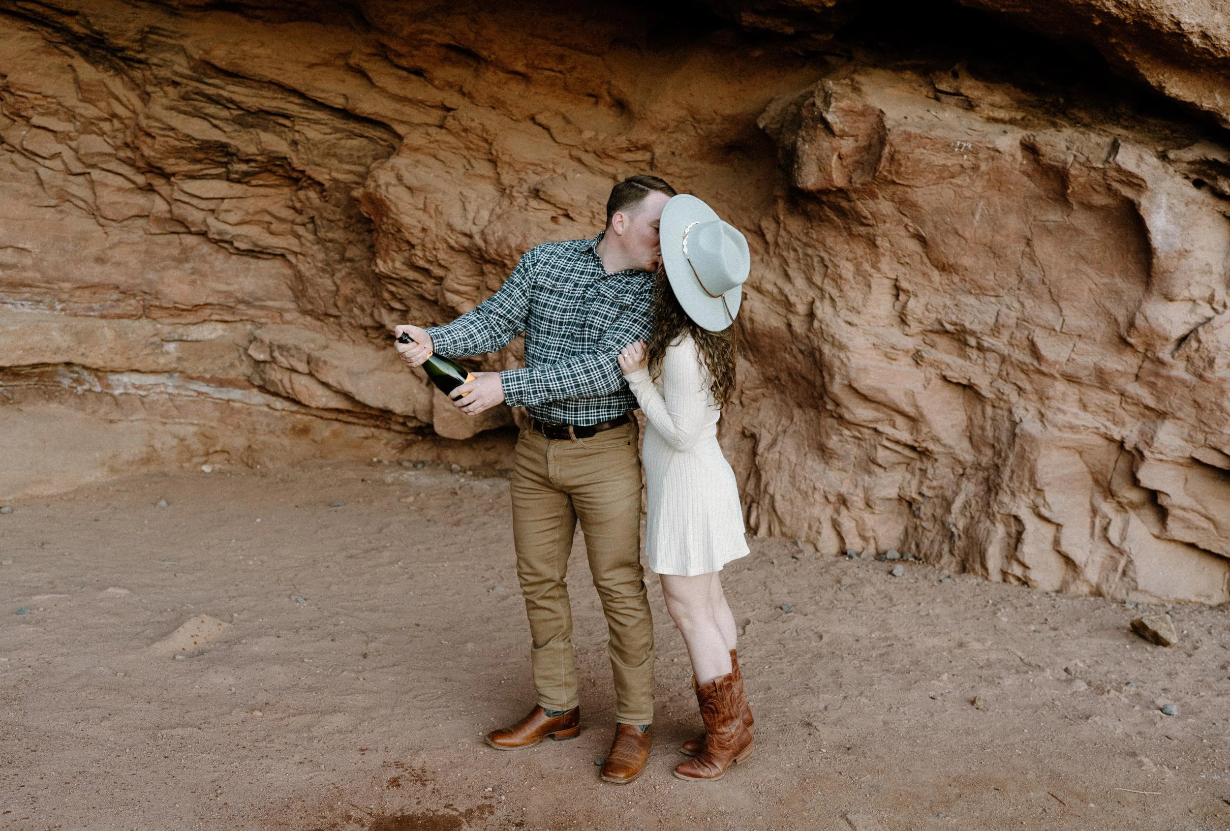 Couple kissing with champagne during an engagement session in Red Rocks