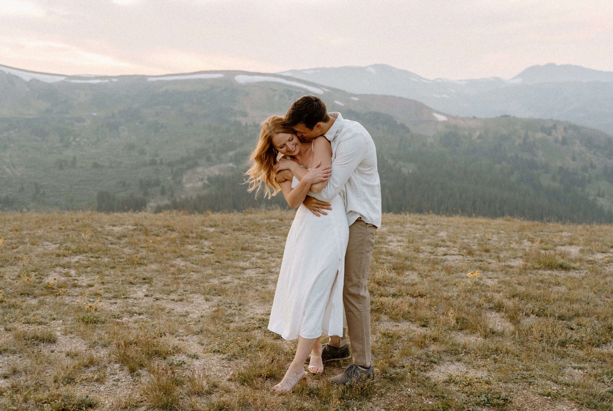 Fiancé hugging fiancée from behind during an engagement session at Loveland Pass