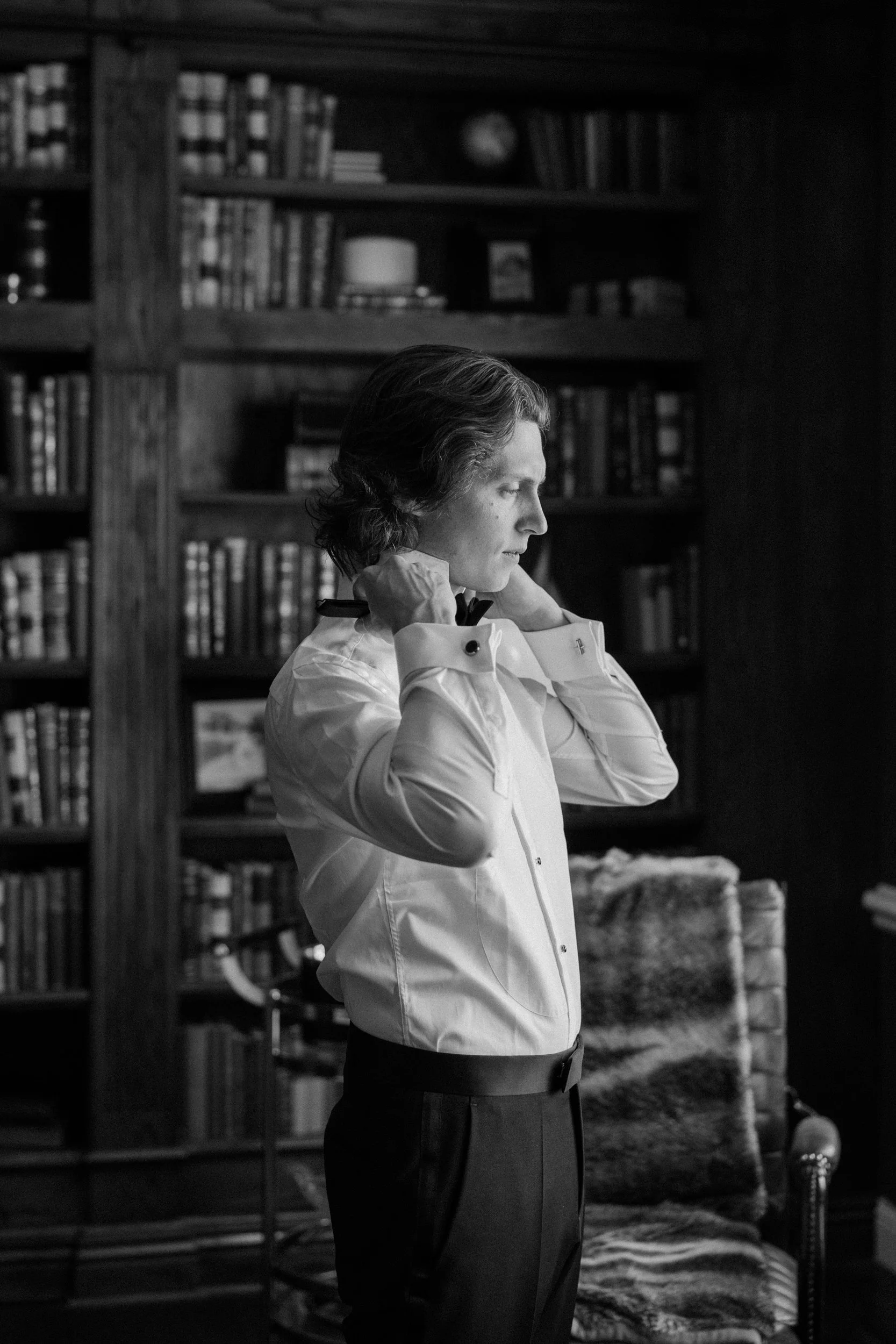 Groom putting on bowtie on wedding day at The Manor House