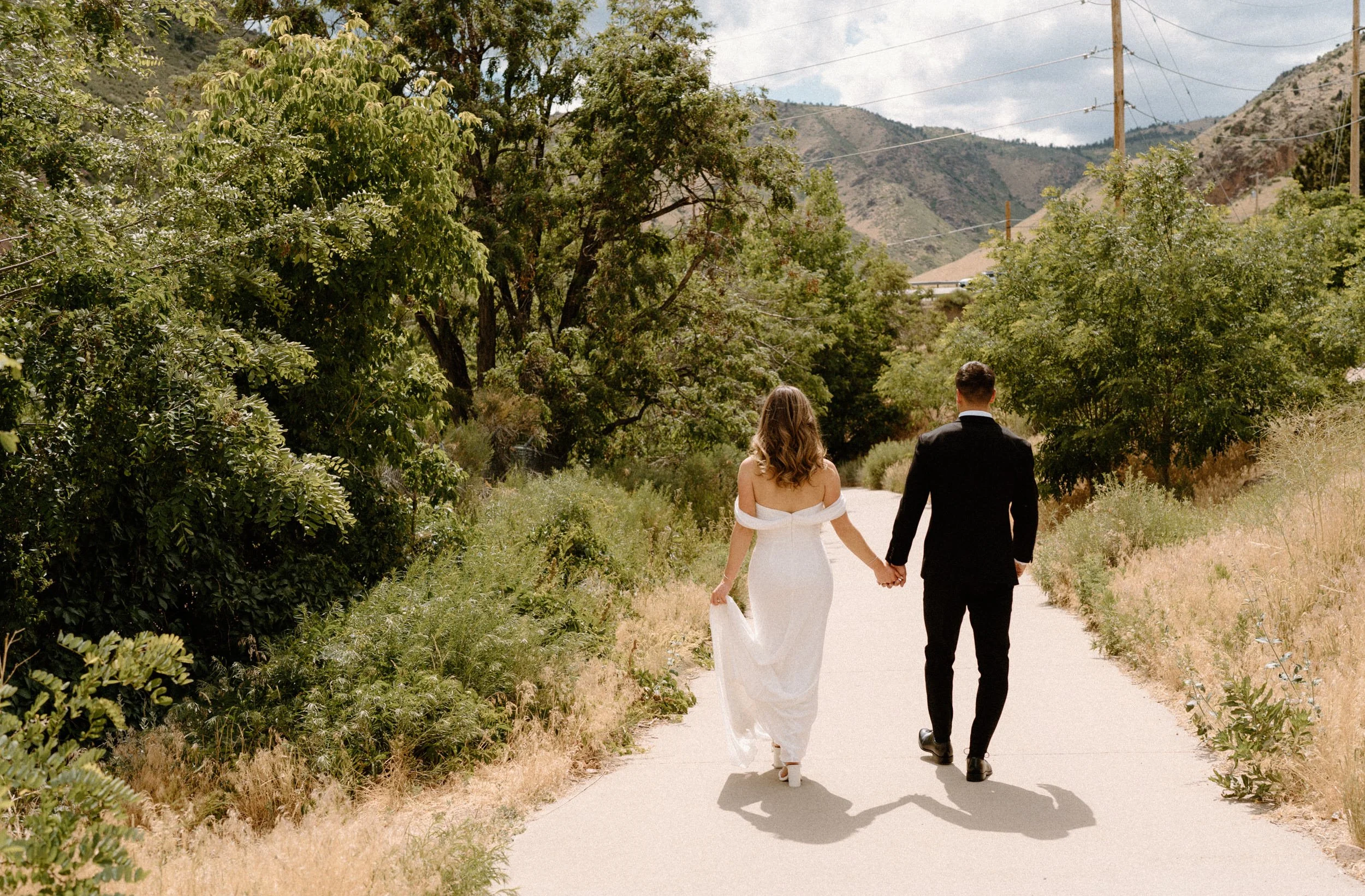 Bride and groom walking down a path on wedding day at The Eddy in Golden Colorado