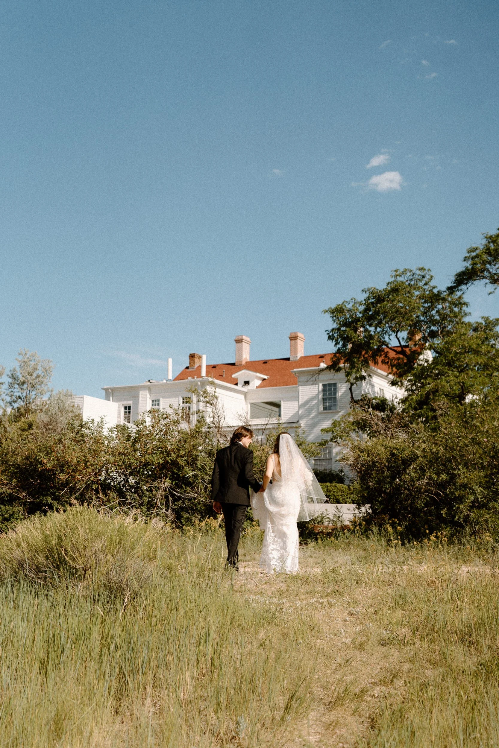 Bride and groom walking towards The Manor House on wedding day