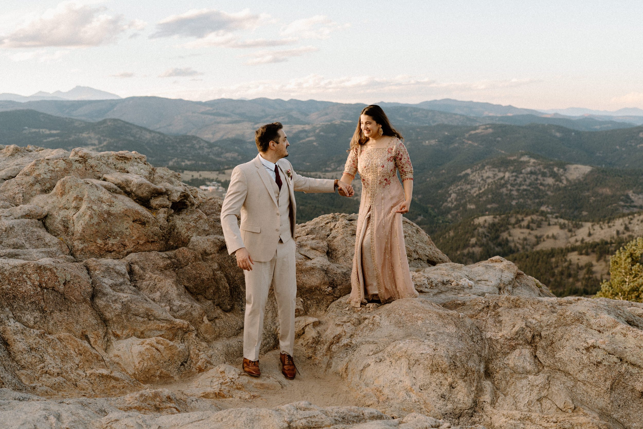 Fiancé helping fiancée off a mountain in Boulder Colorado during an engagement session