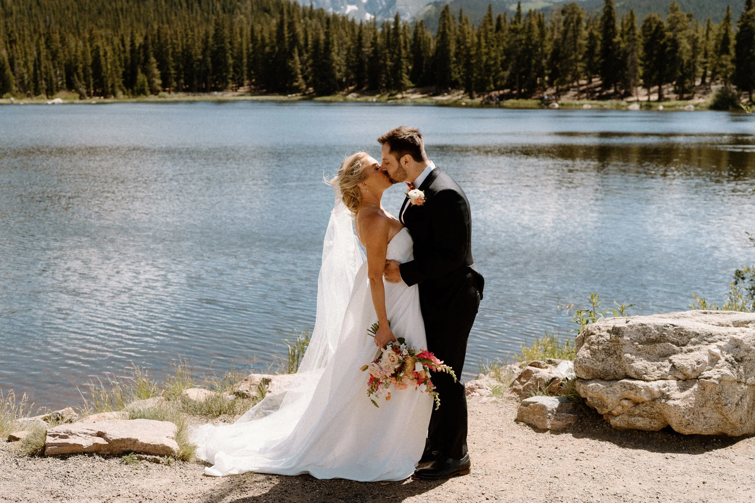 Bride and groom kissing at a lake on wedding day at Blackstone Rivers Ranch