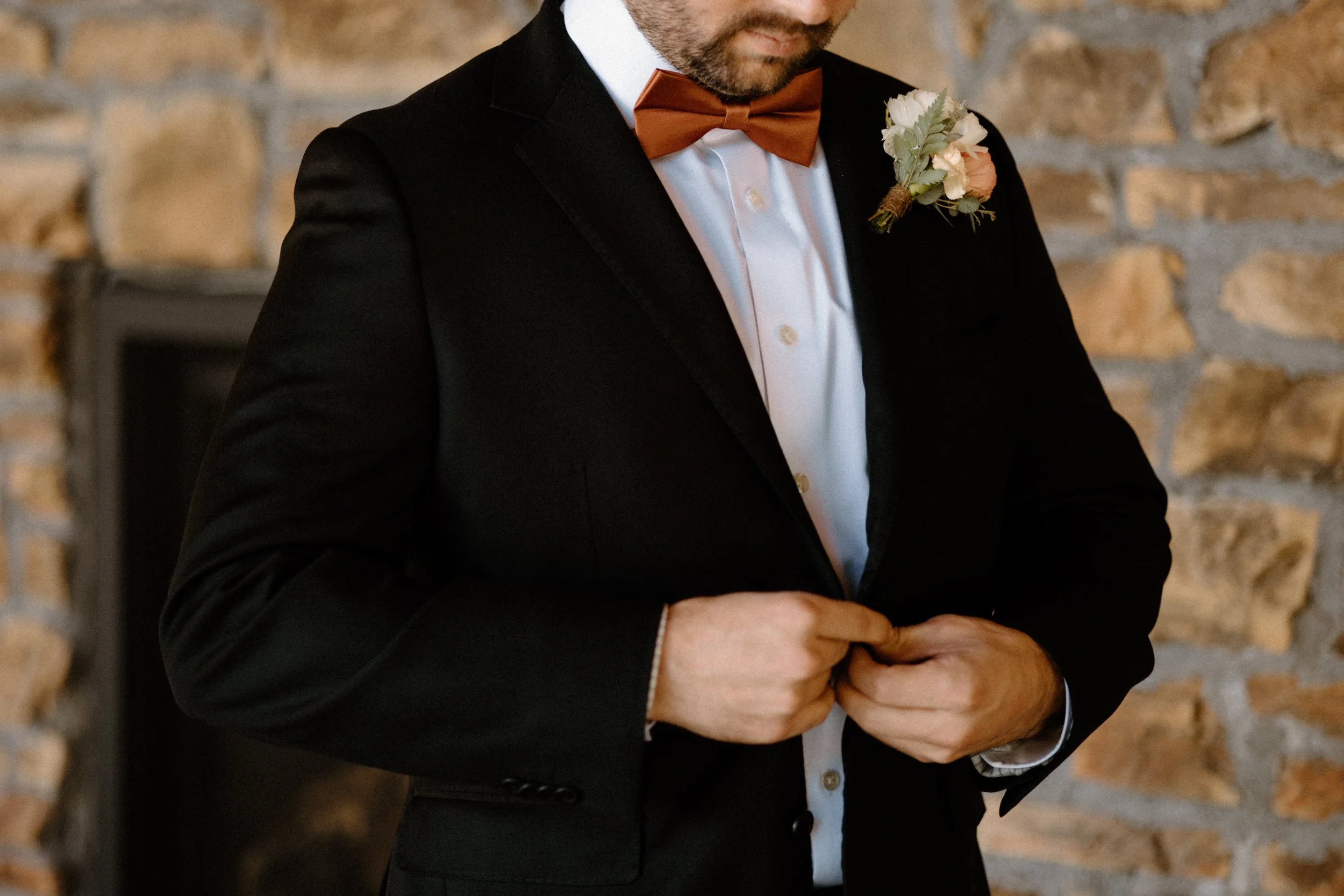 Groom buttoning jacket on wedding day at Blackstone Rivers Ranch