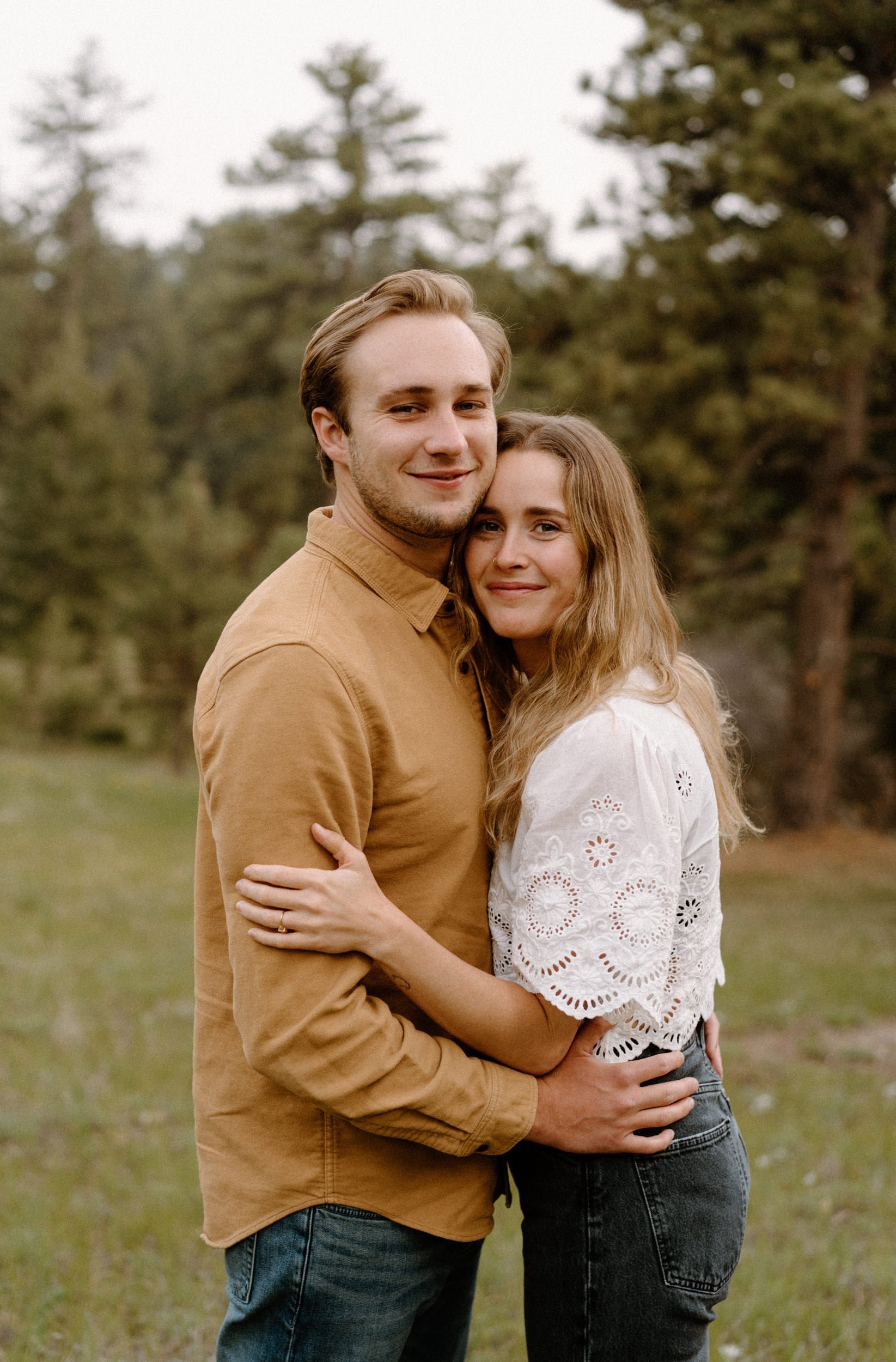 Man and woman pose and smile at the camera during engagement session