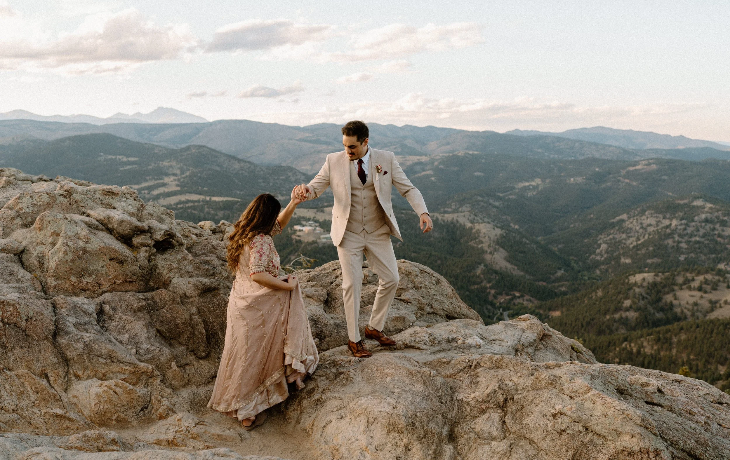 Fiancé helping fiancée up a mountain in Boulder Colorado during an engagement session