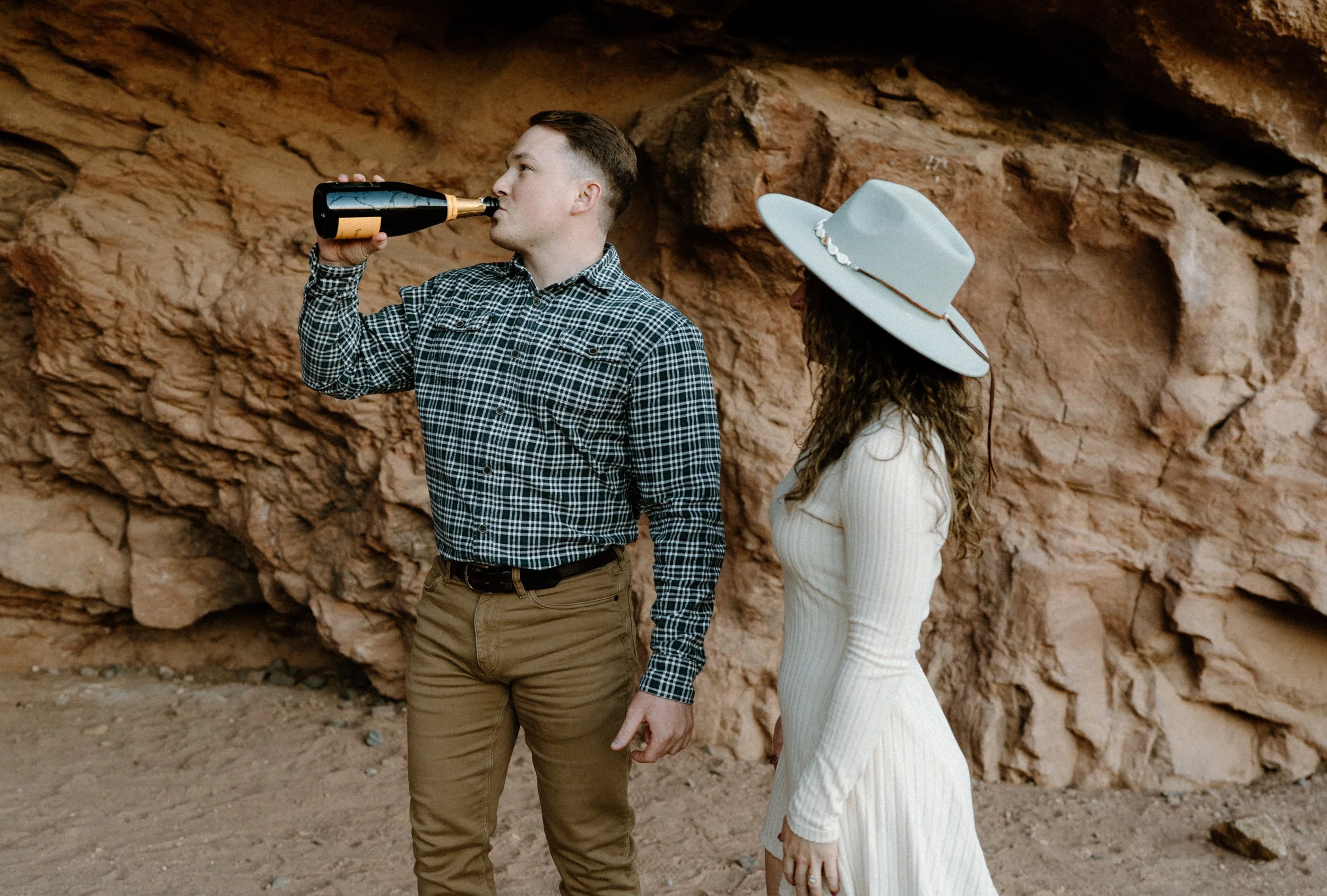 Fiancé drinking champagne during an engagement session at Red Rocks