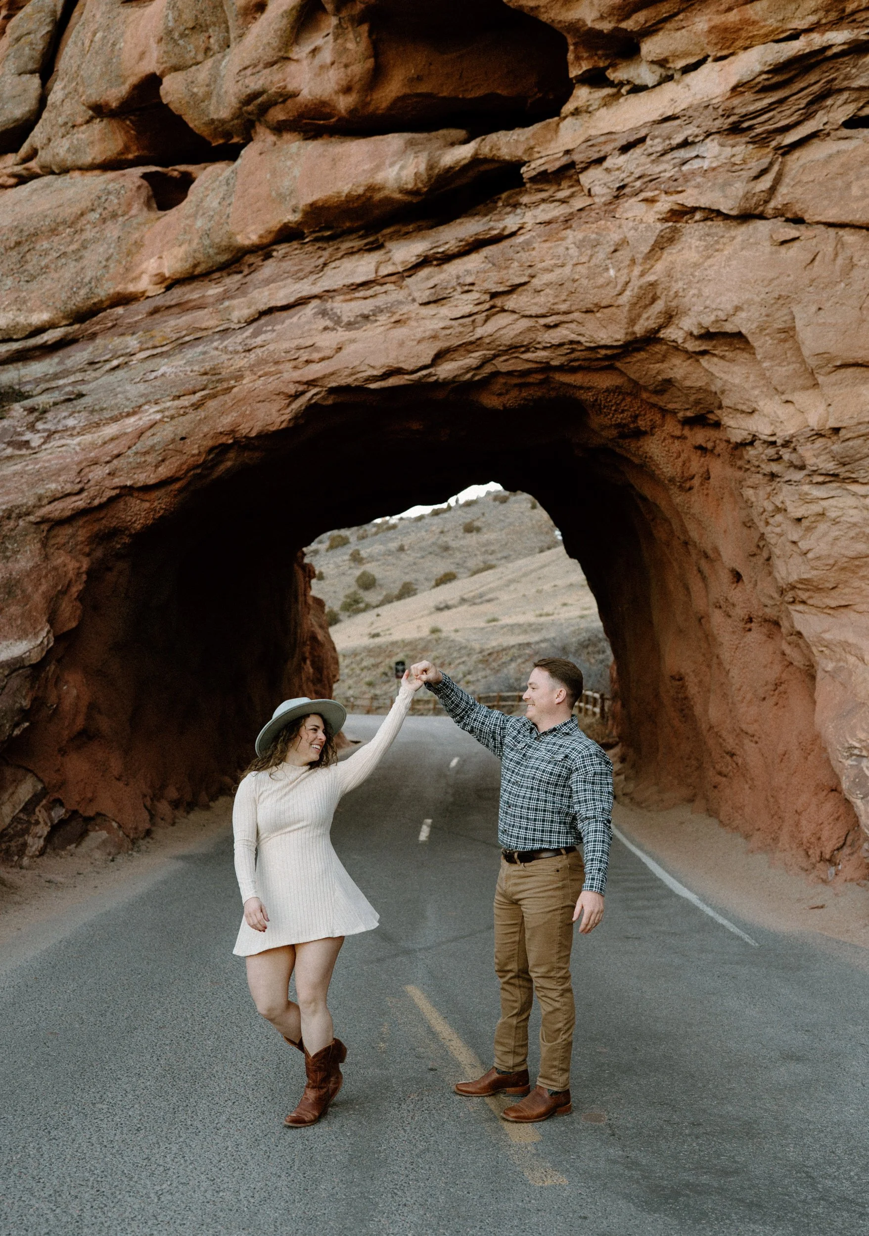 Fiancé spinning fiancée in a tunnel during engagement session at Red Rocks