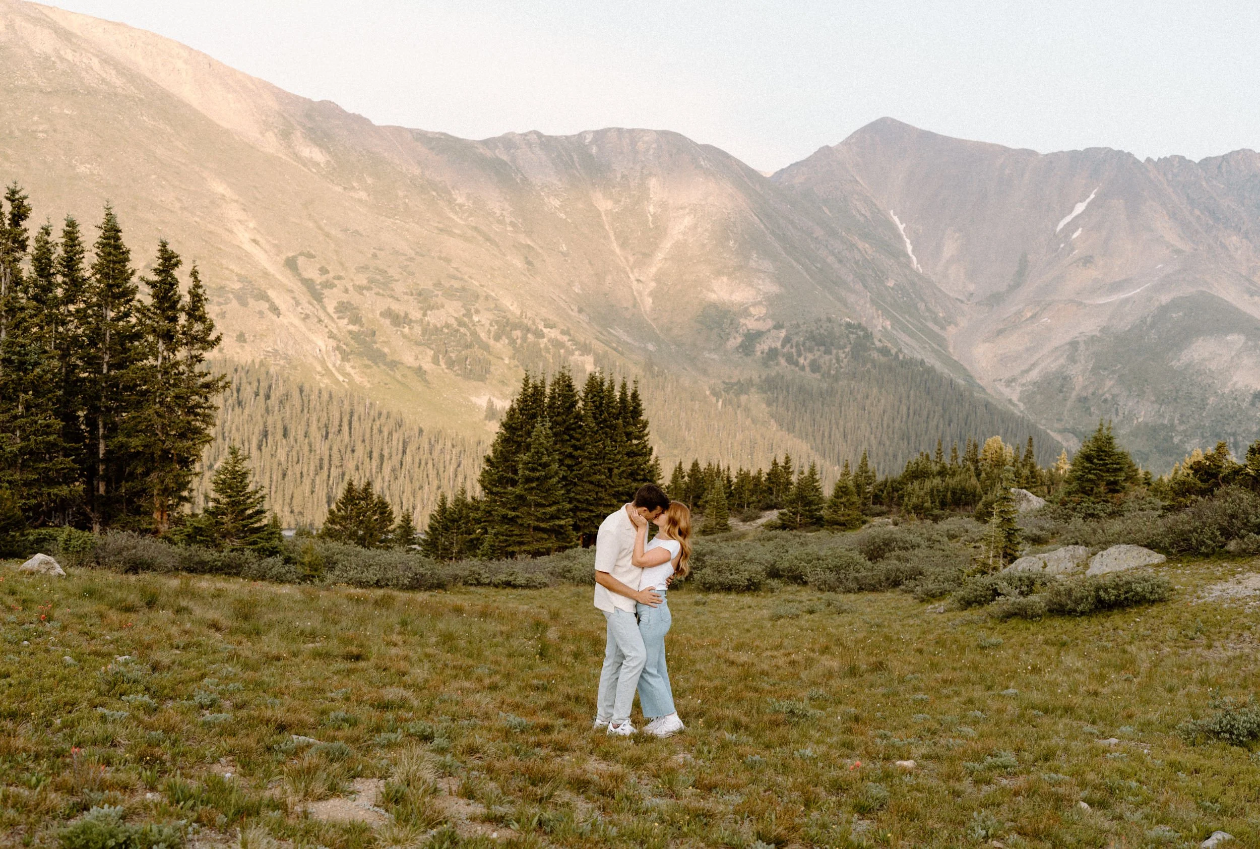 Couple kissing in a field during an engagement session at Loveland Pass