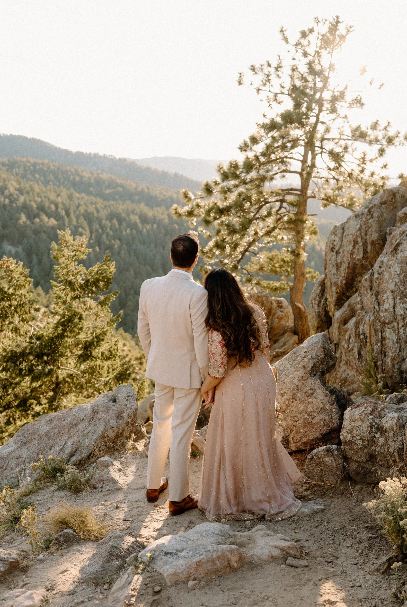 Couple standing on a mountain admiring the view during an engagement session in Boulder Colorado