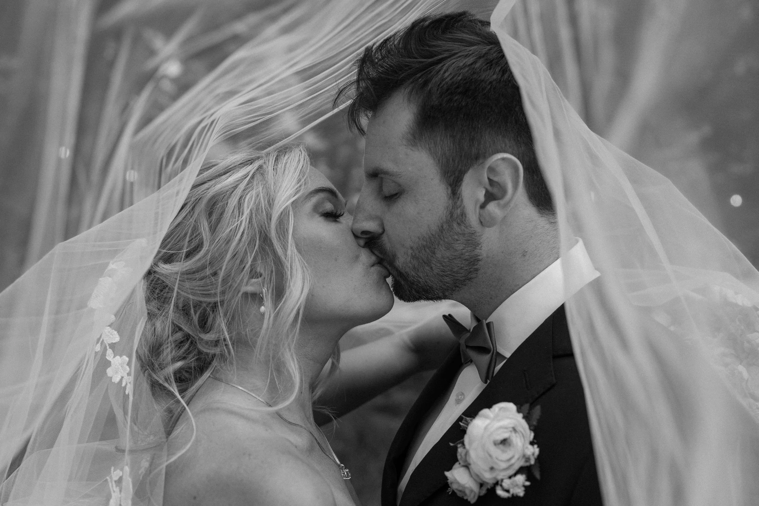 Bride and groom kissing under vail on wedding day at Blackstone Rivers Ranch