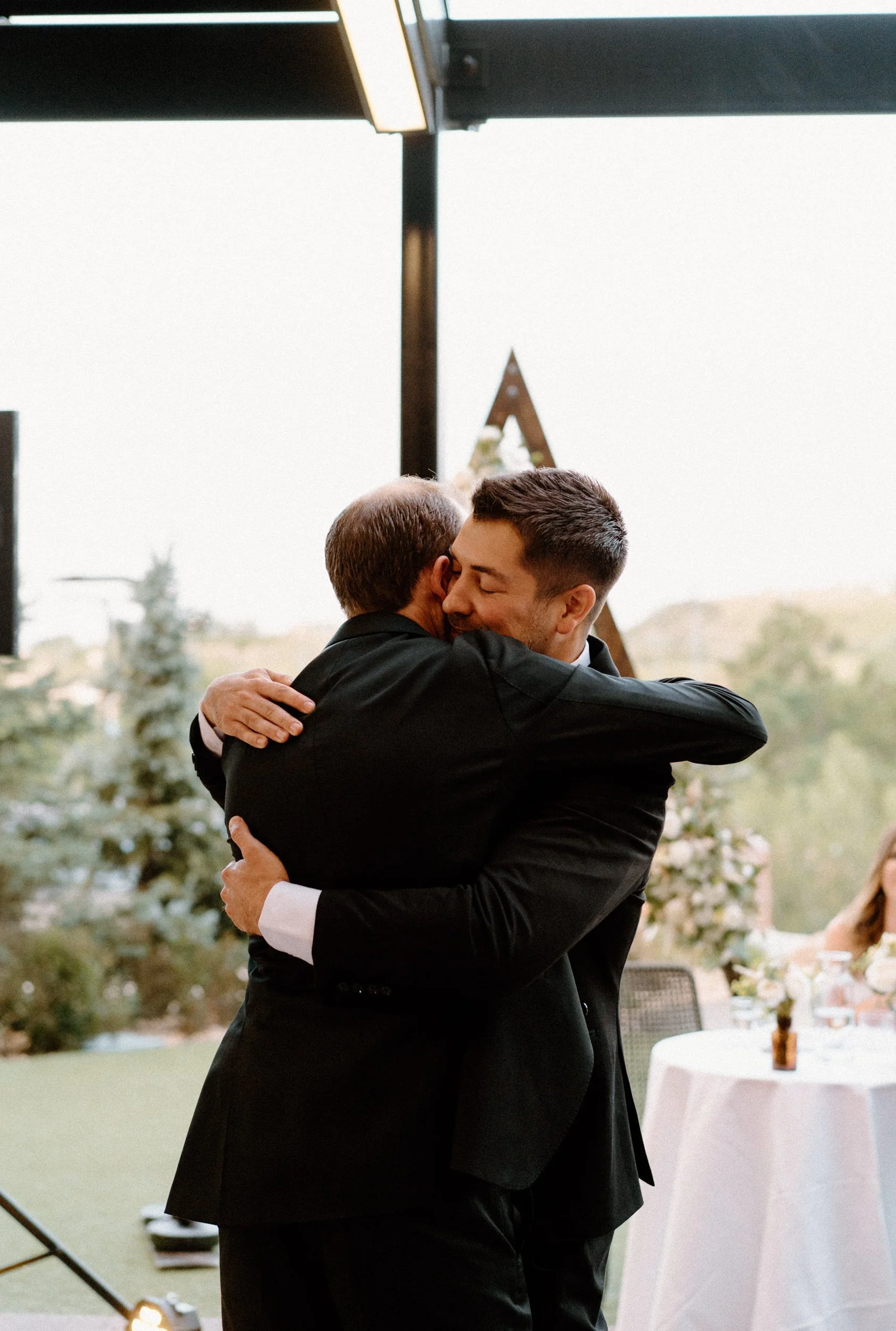 Groom and friend hugging on wedding day at The Eddy in Golden Colorado