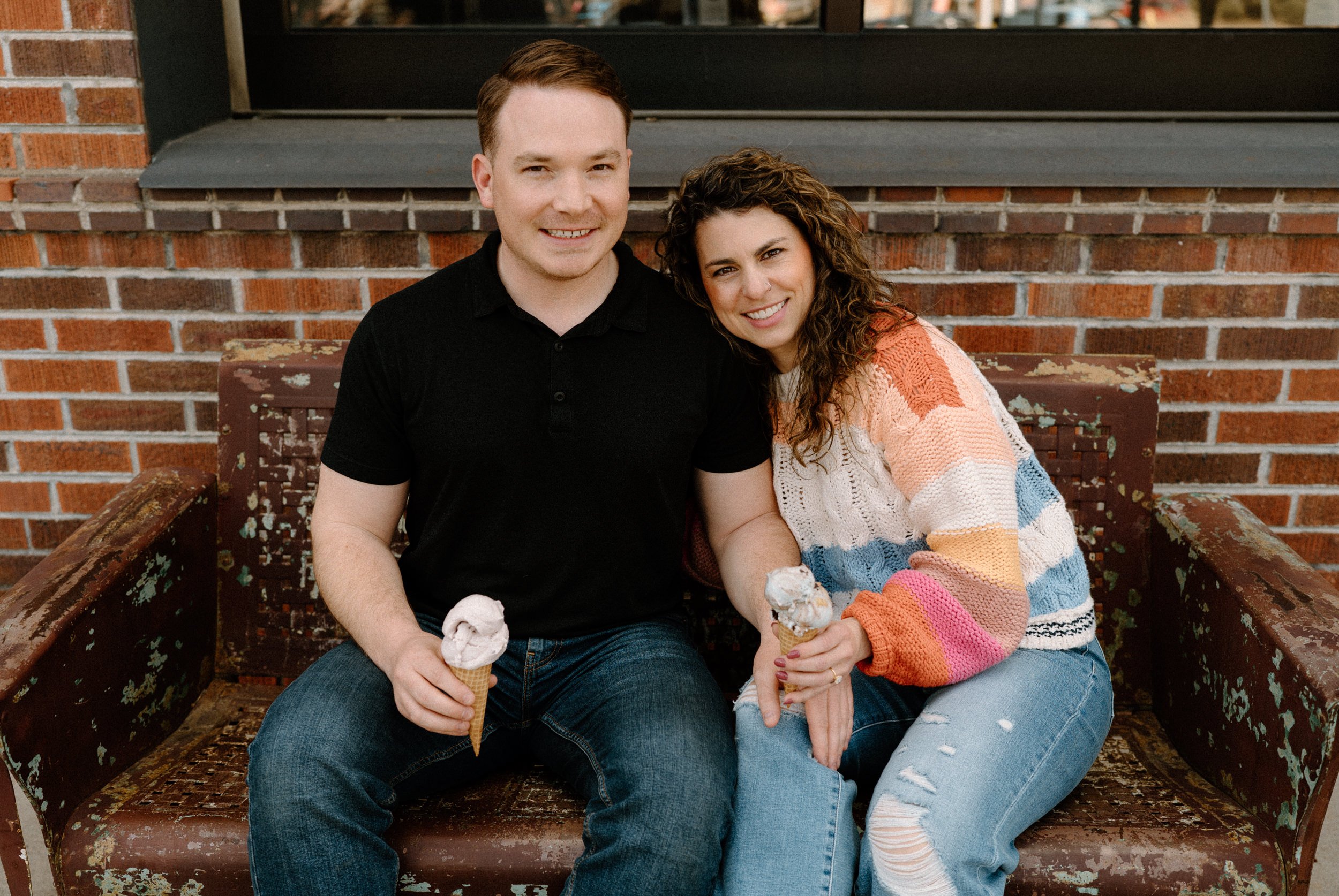 Couple sitting on a bench outside Little Man's ice cream during engagement session