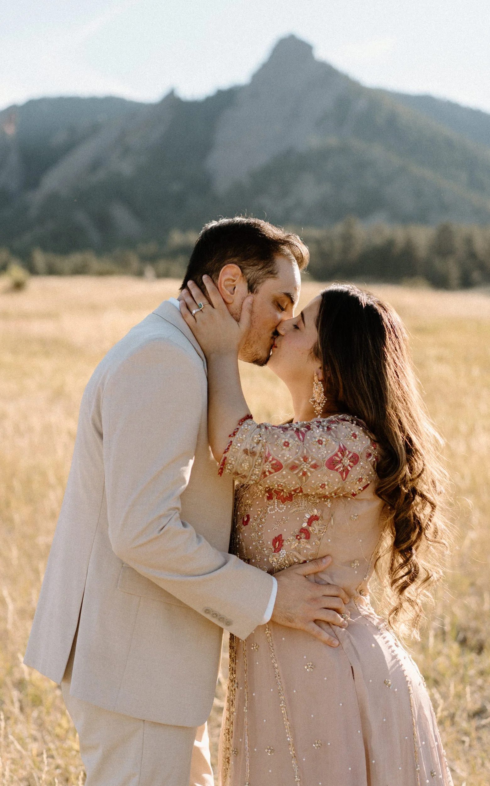 Couple kissing in front of the Flatirons during an engagement session in Boulder Colorado