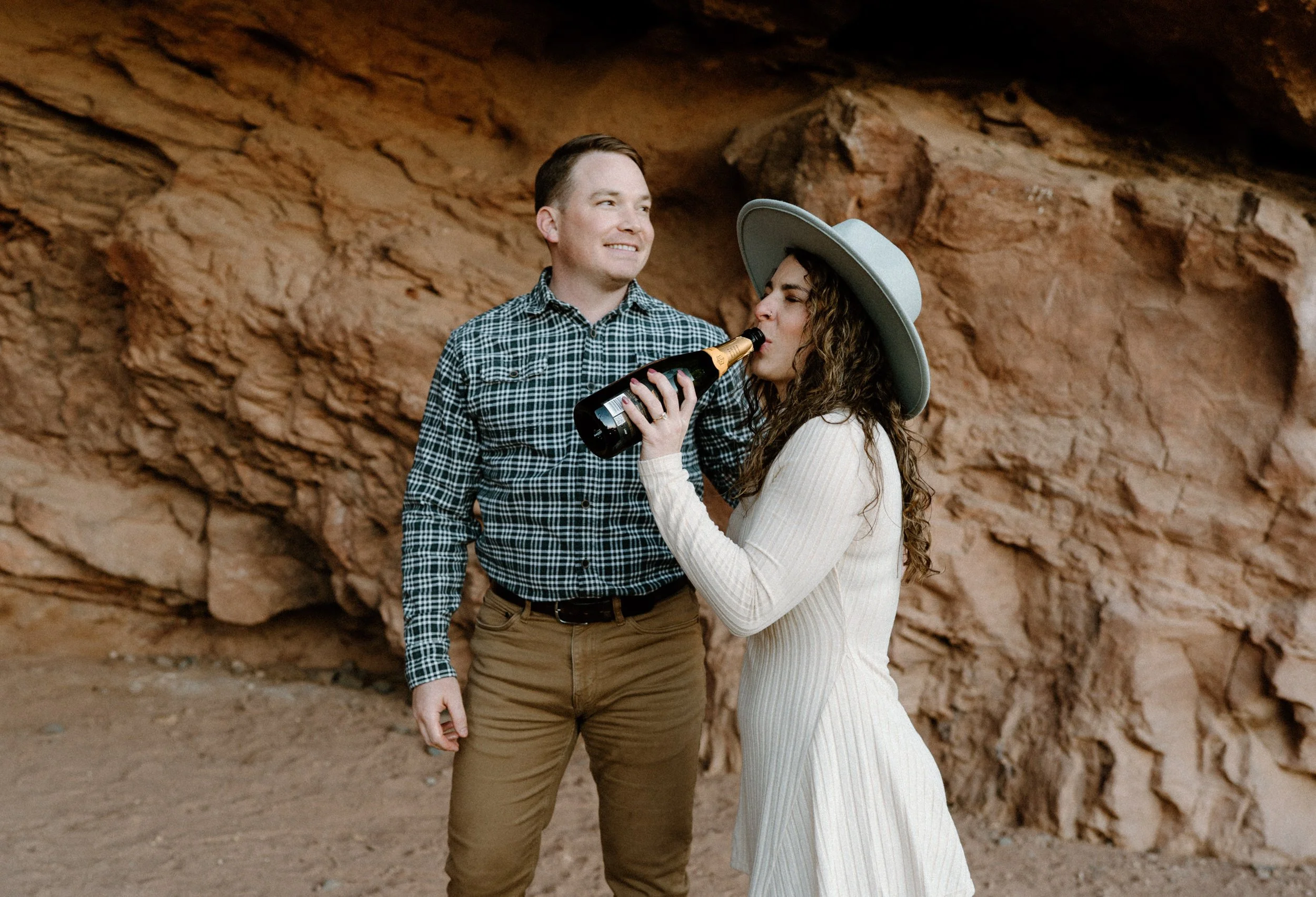 Fiancée drinking champagne during engagement session in Red Rocks