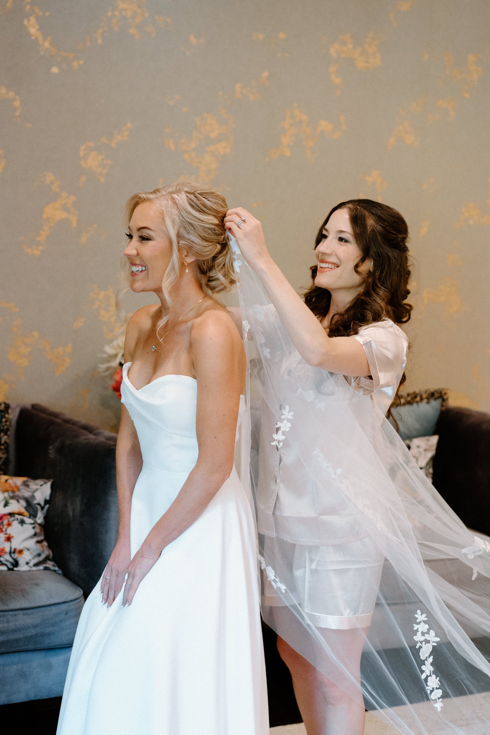 Bridesmaid putting on bride's vail on wedding day at Blackstone Rivers Ranch