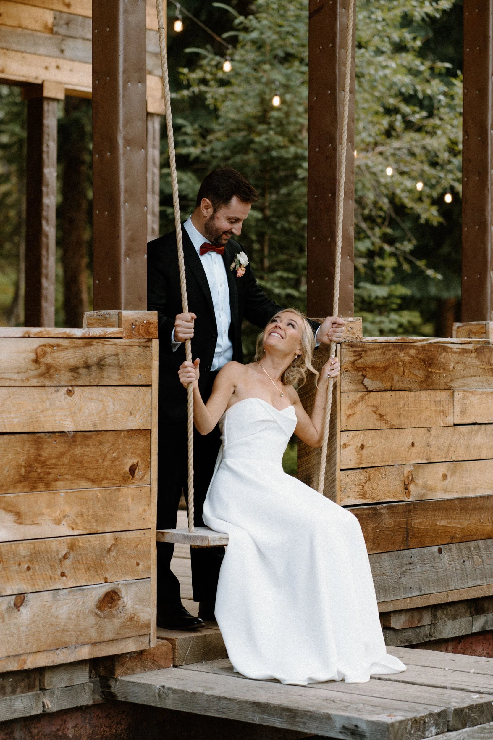 Bride smiling at groom on a swing at Blackstone Rivers Ranch