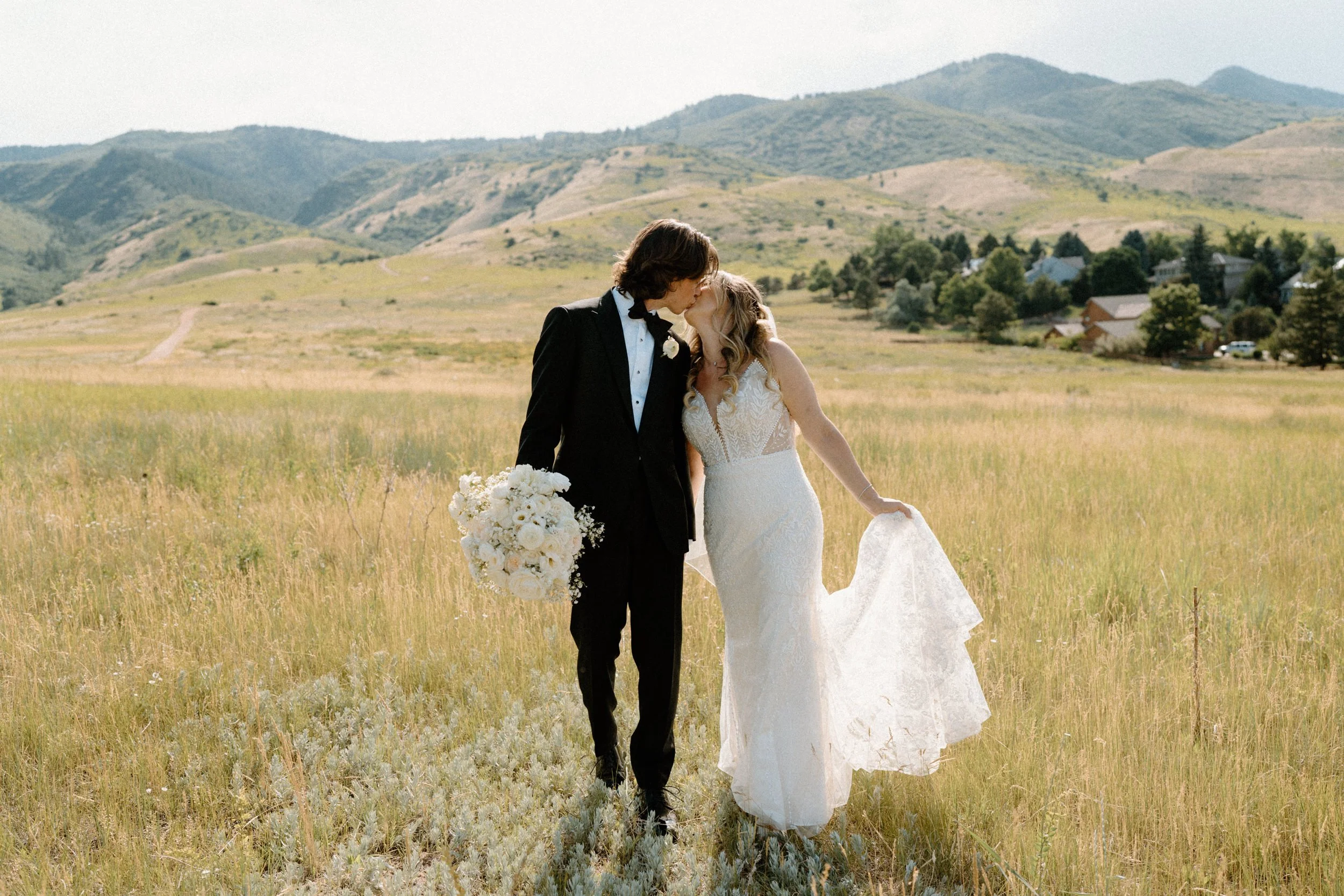 Bride and groom kissing while walking in a field on wedding day at The Manor House