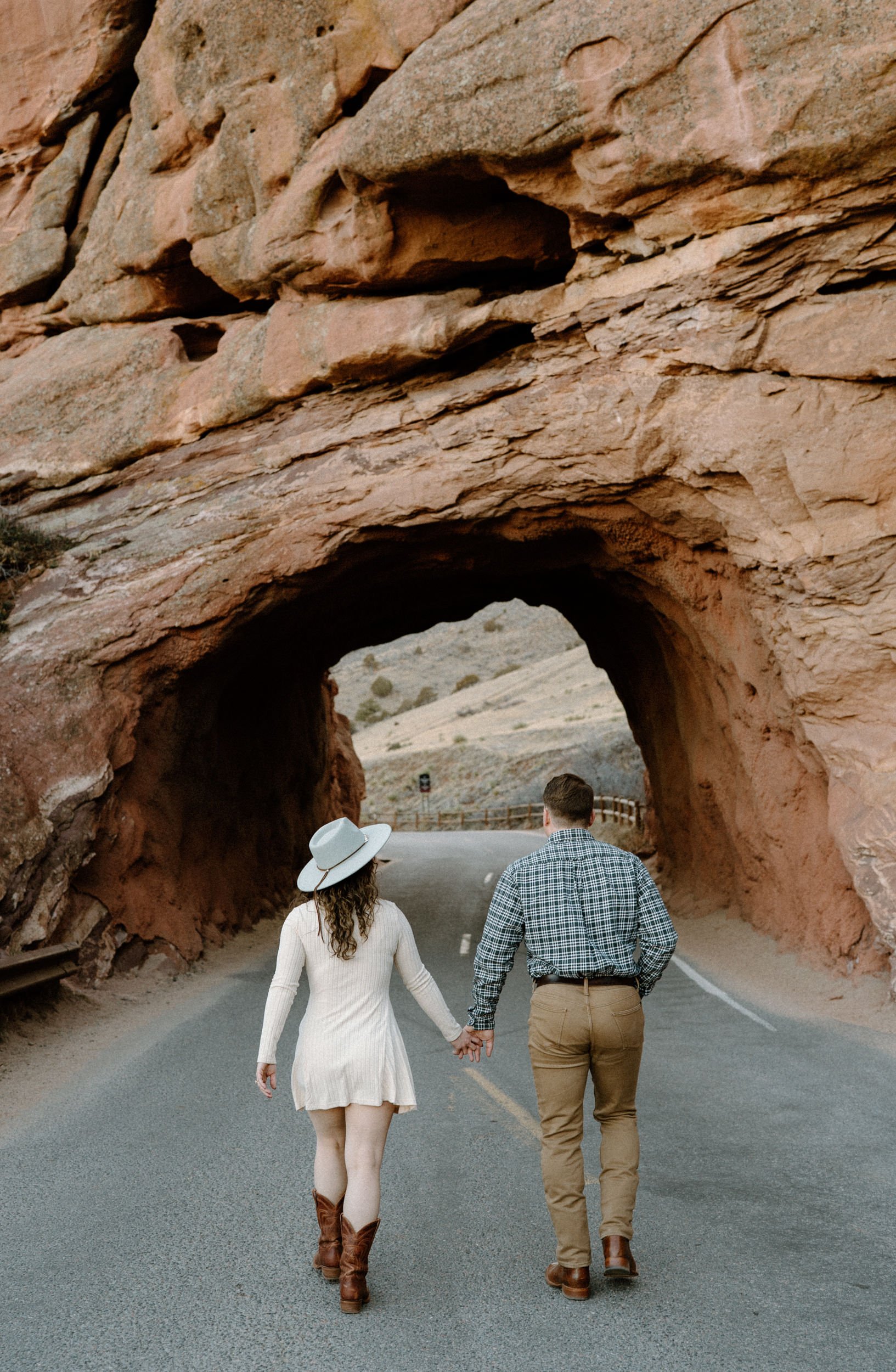 Couple walking into tunnel during engagement session at Red Rocks