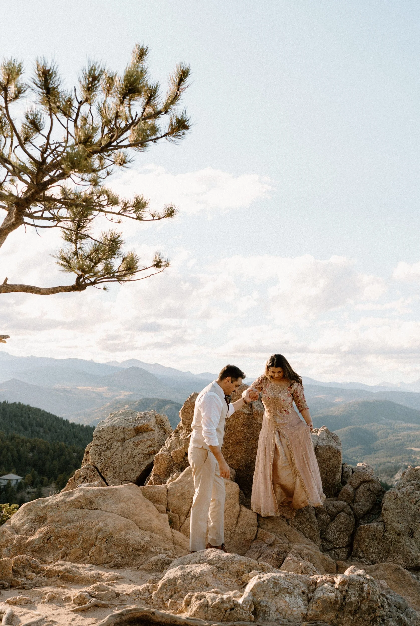 Fiancé helping his fiancée down a mountain during an engagement session in Boulder Colorado