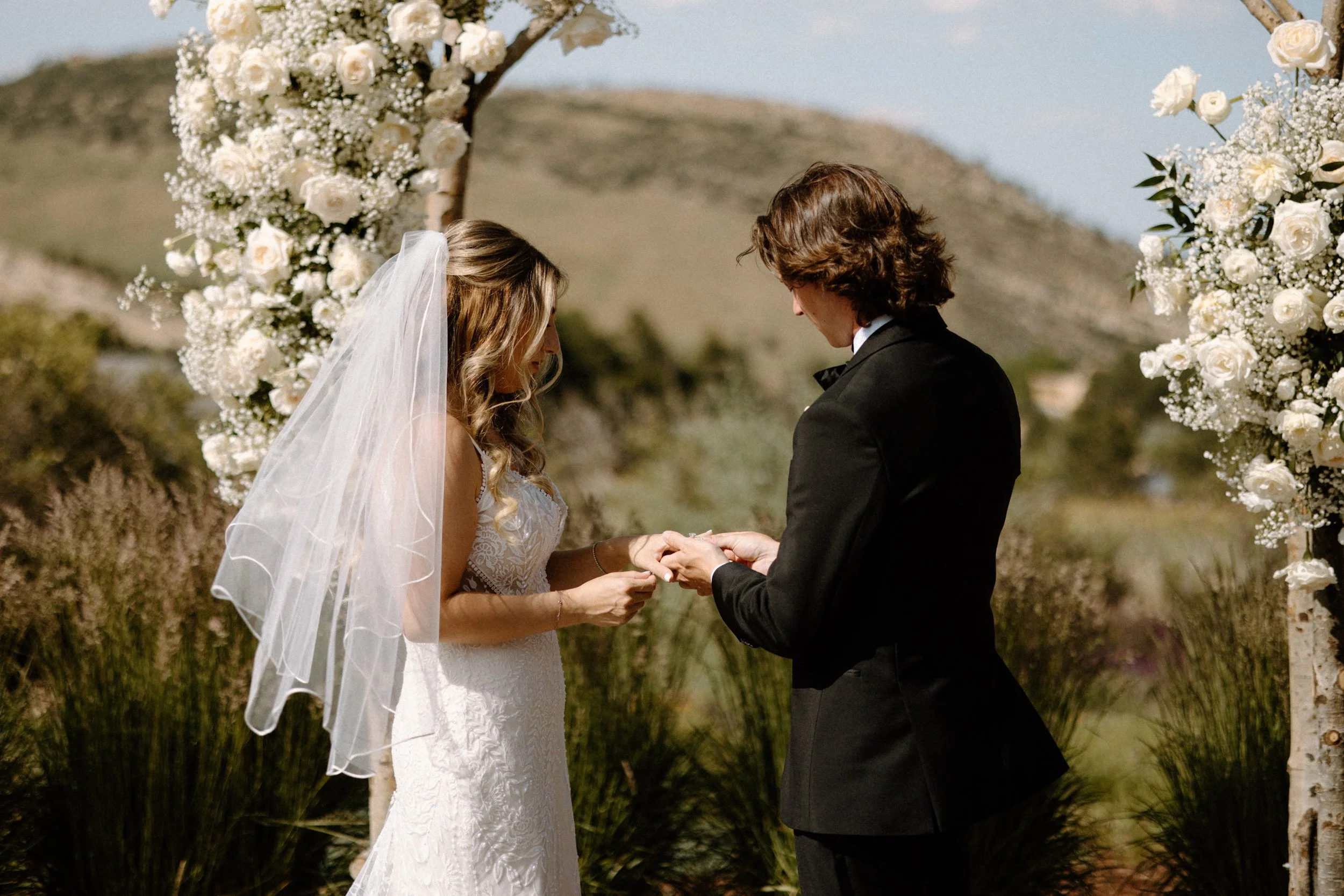 Groom putting on bride's ring during the ceremony at The Manor House