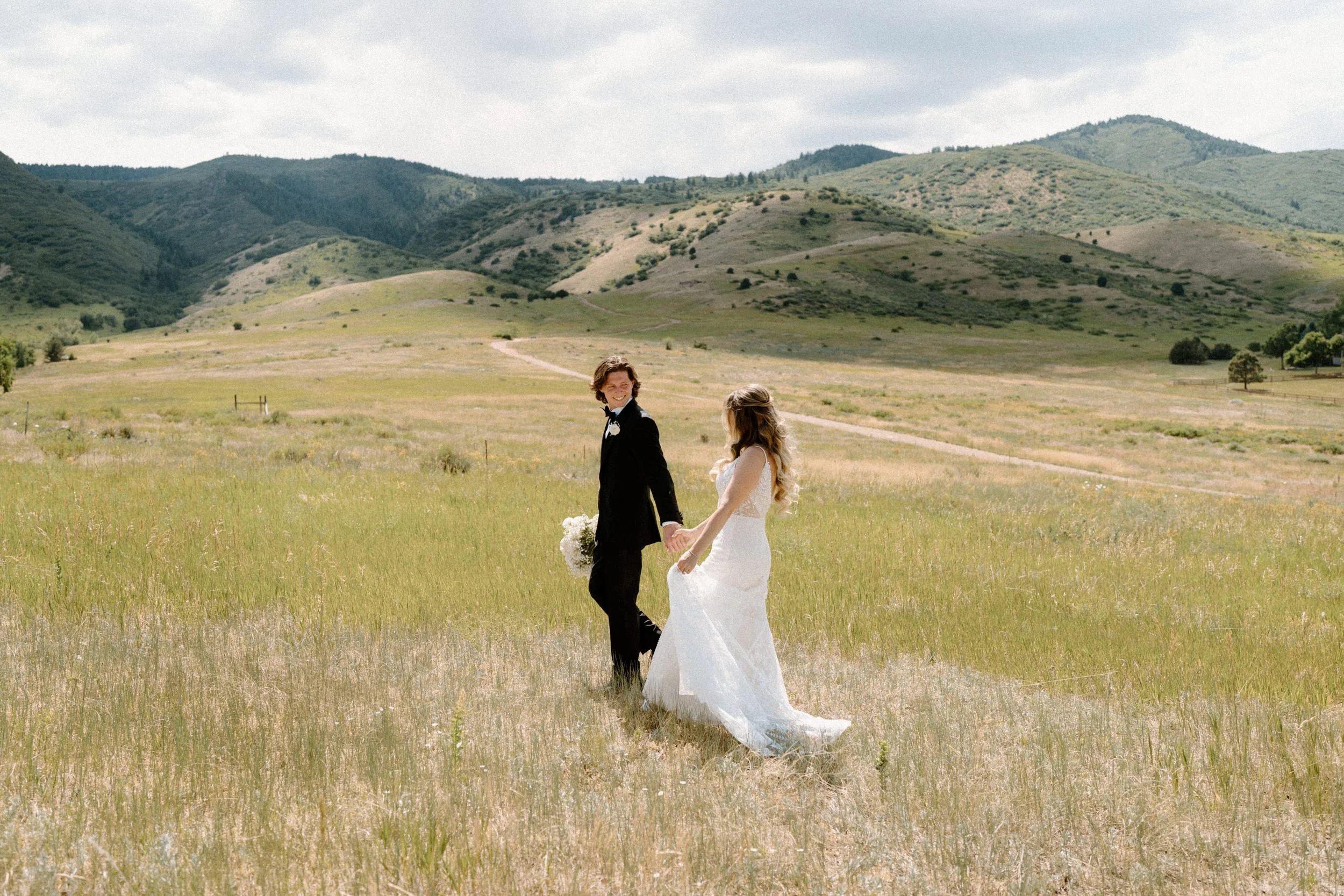 Bride and groom walking in a field and holding hands on wedding day at The Manor House