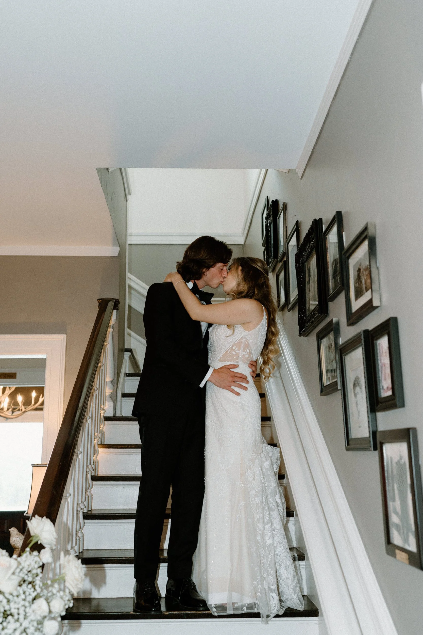 Bride and groom kissing on the stairs inside The Manor House on wedding day