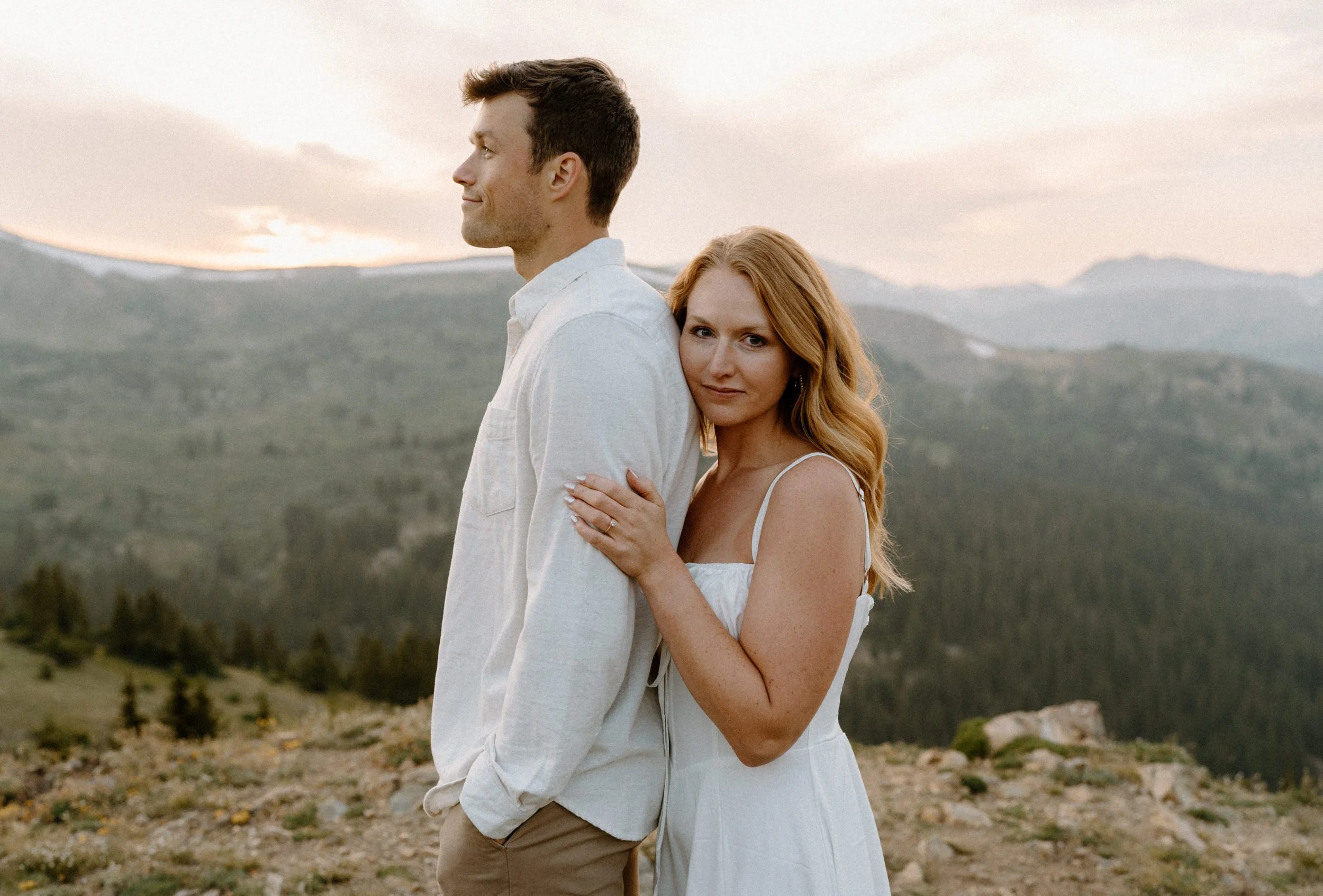 Fiancée hugging fiancé while looking at the camera during engagement session at Loveland Pass