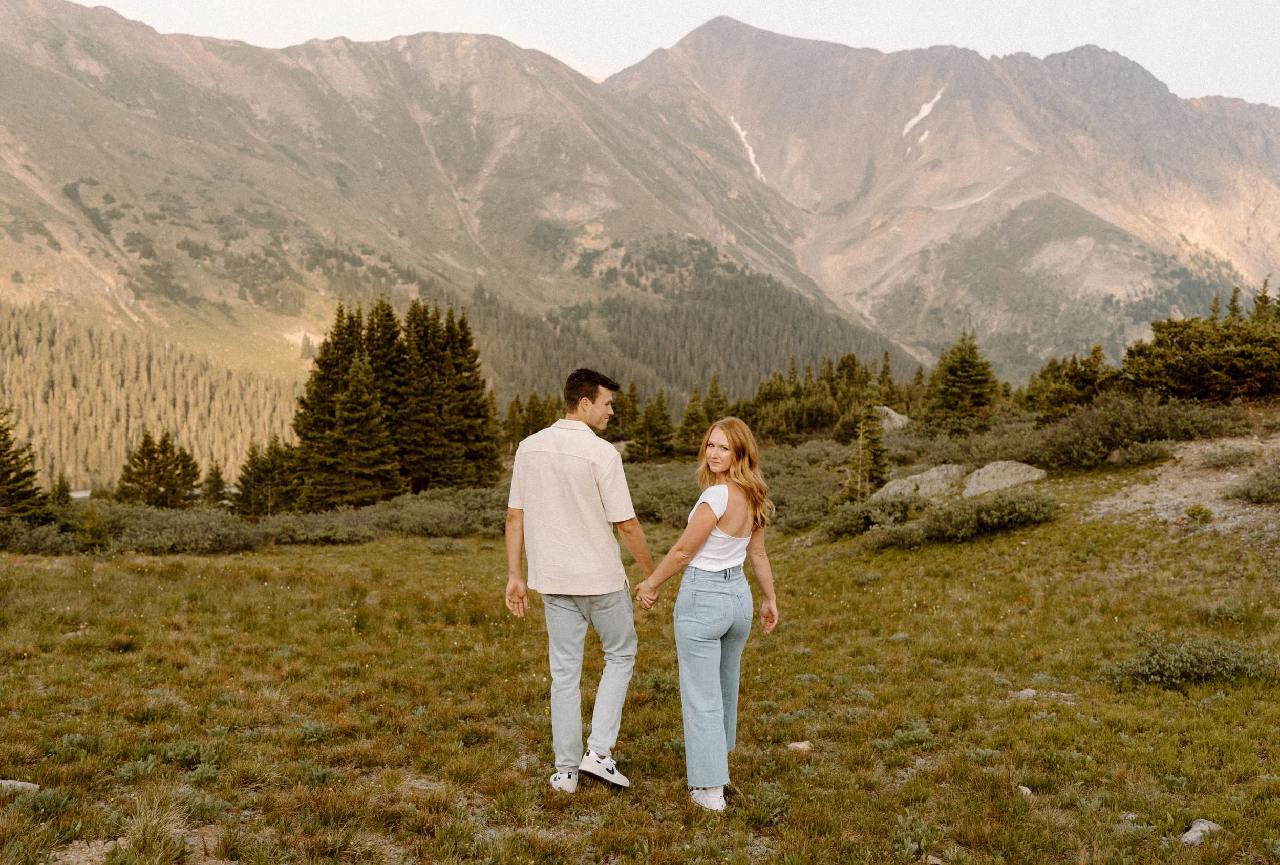 Couple walking in a field during engagement session at Loveland Pass