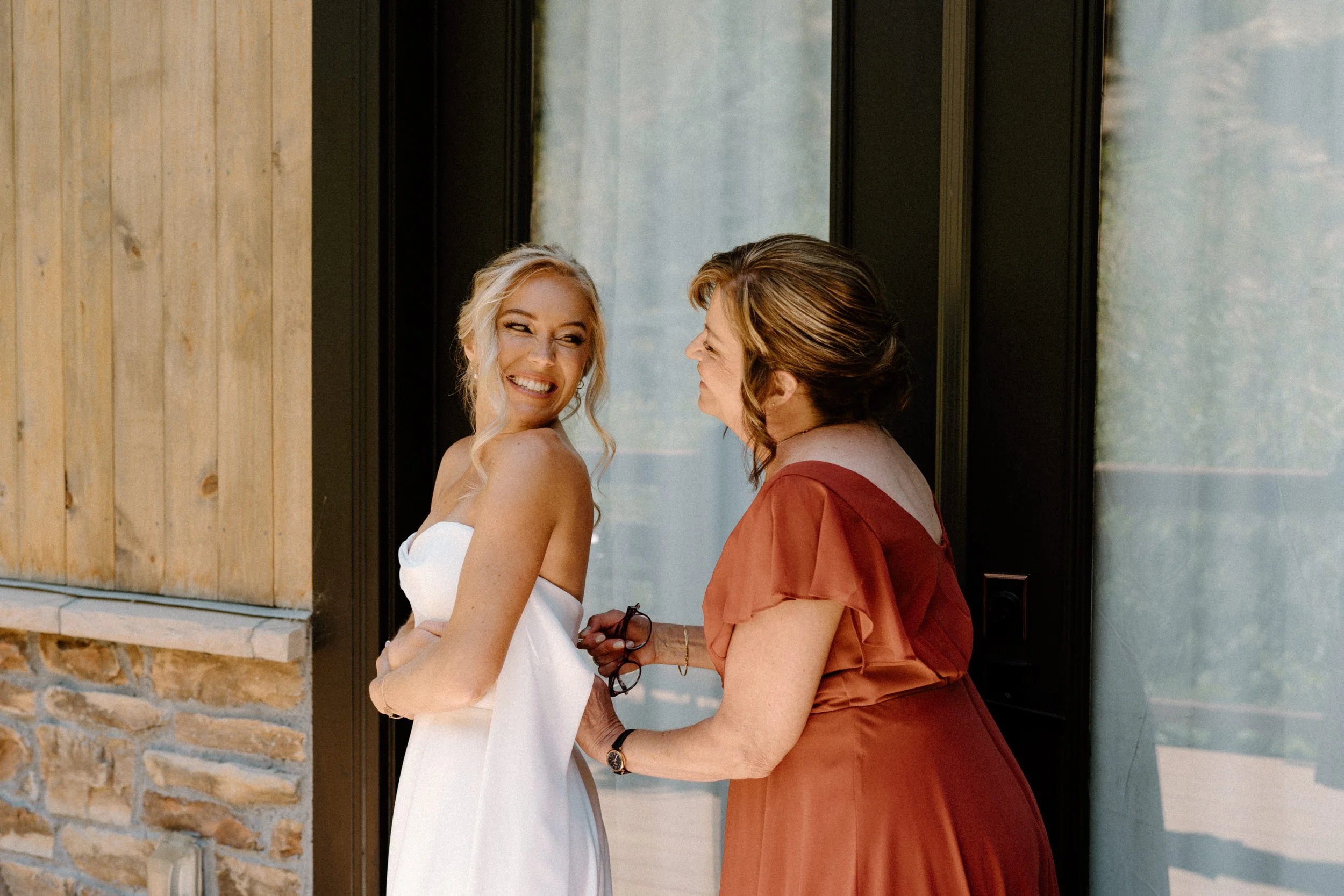 Bride's mom zipping brides dress on wedding day at Blackstone Rivers Ranch
