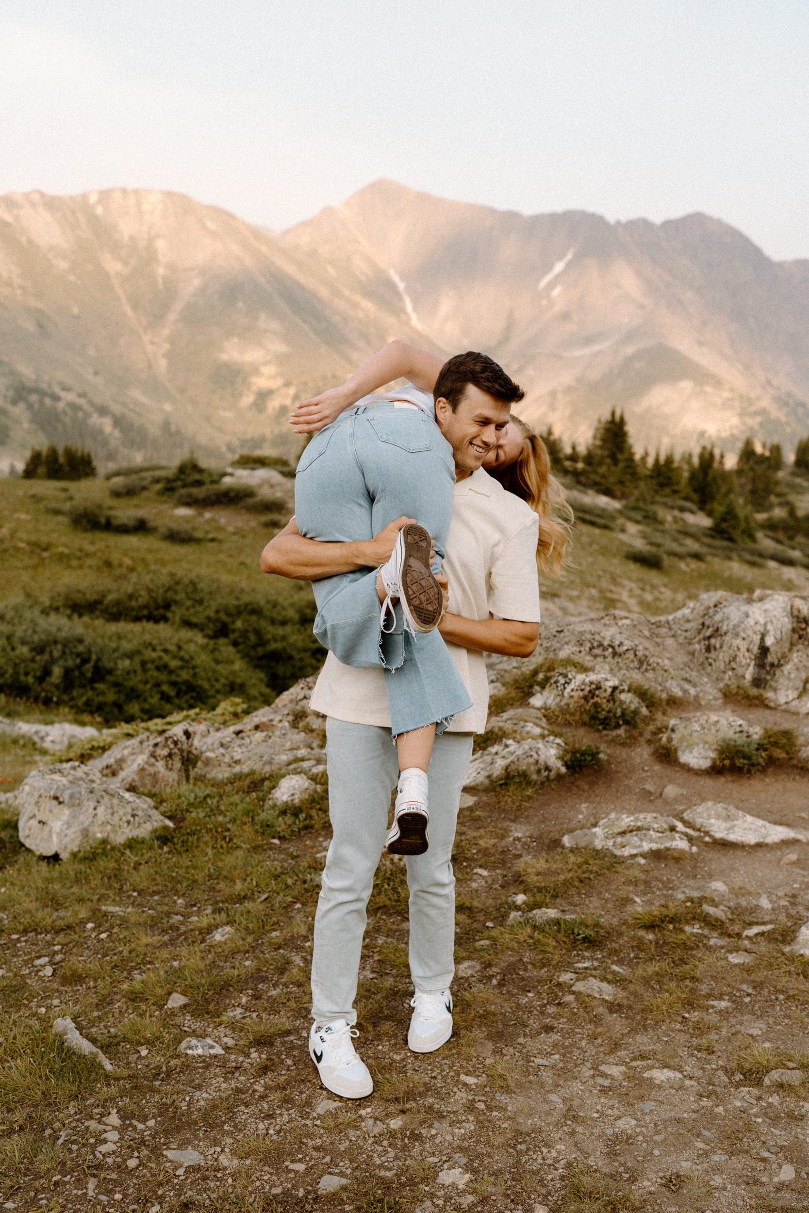 Fiancé throwing fiancée over his shoulder during an engagement session at Loveland Pass