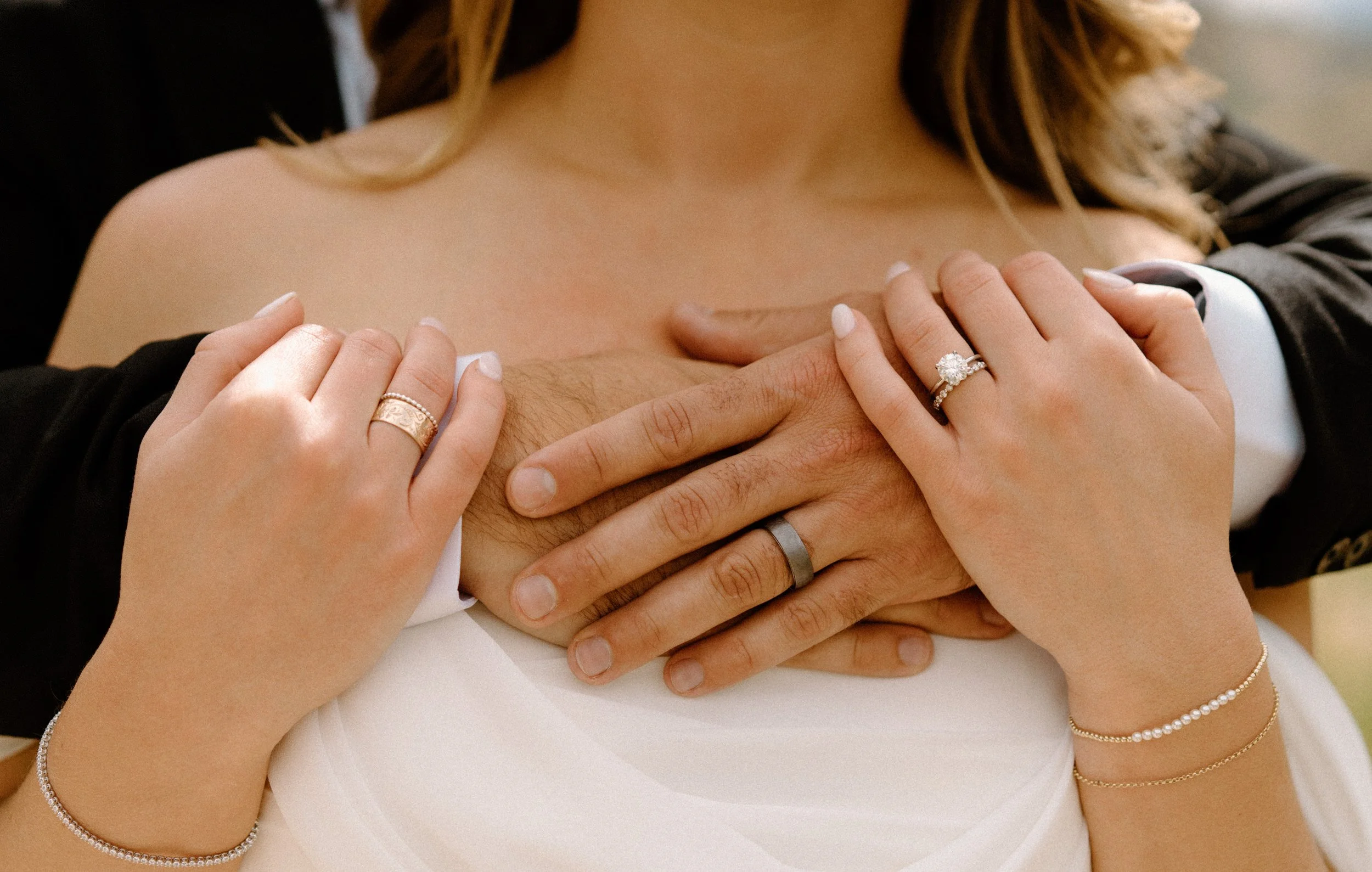 Groom's hands wrapped around bride's shoulder showing wedding rings at The Eddy in Golden Colorado