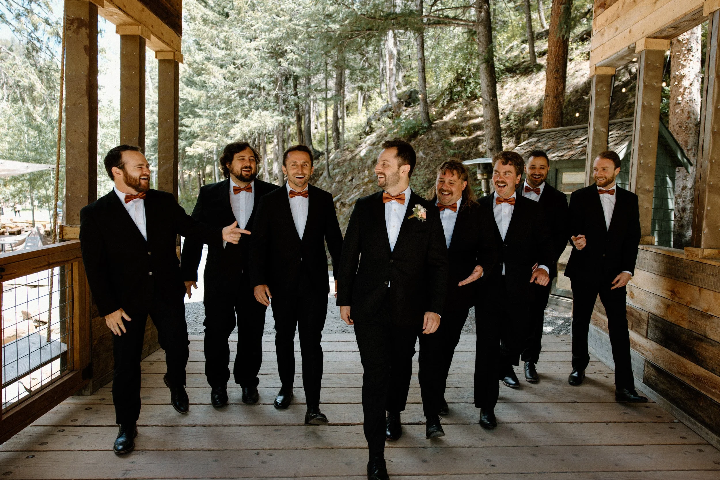 Groom and groomsmen laughing and walking on wedding day at Blackstone Rivers Ranch