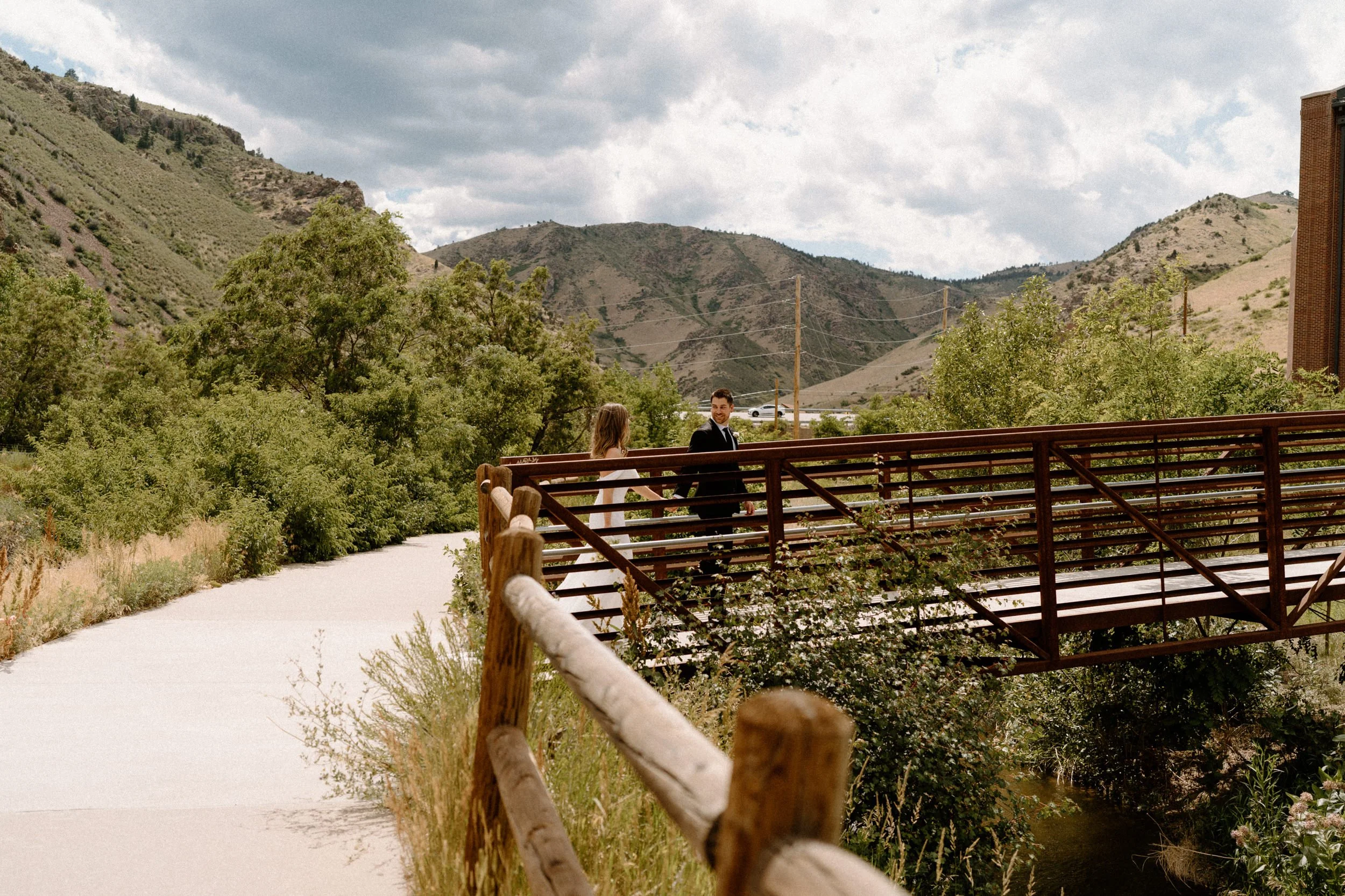 Bride and groom walking on a bridge on wedding day at The Eddy in Golden Colorado